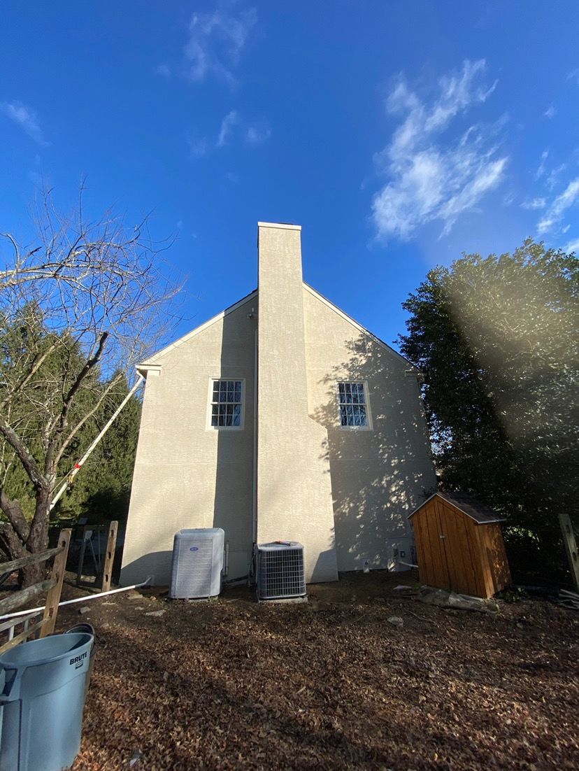 A white house with a chimney on the side of it.