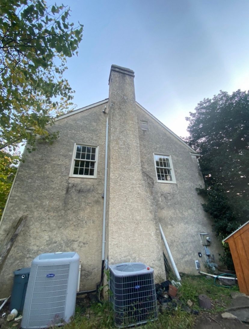 The back of a house with a chimney and air conditioner.
