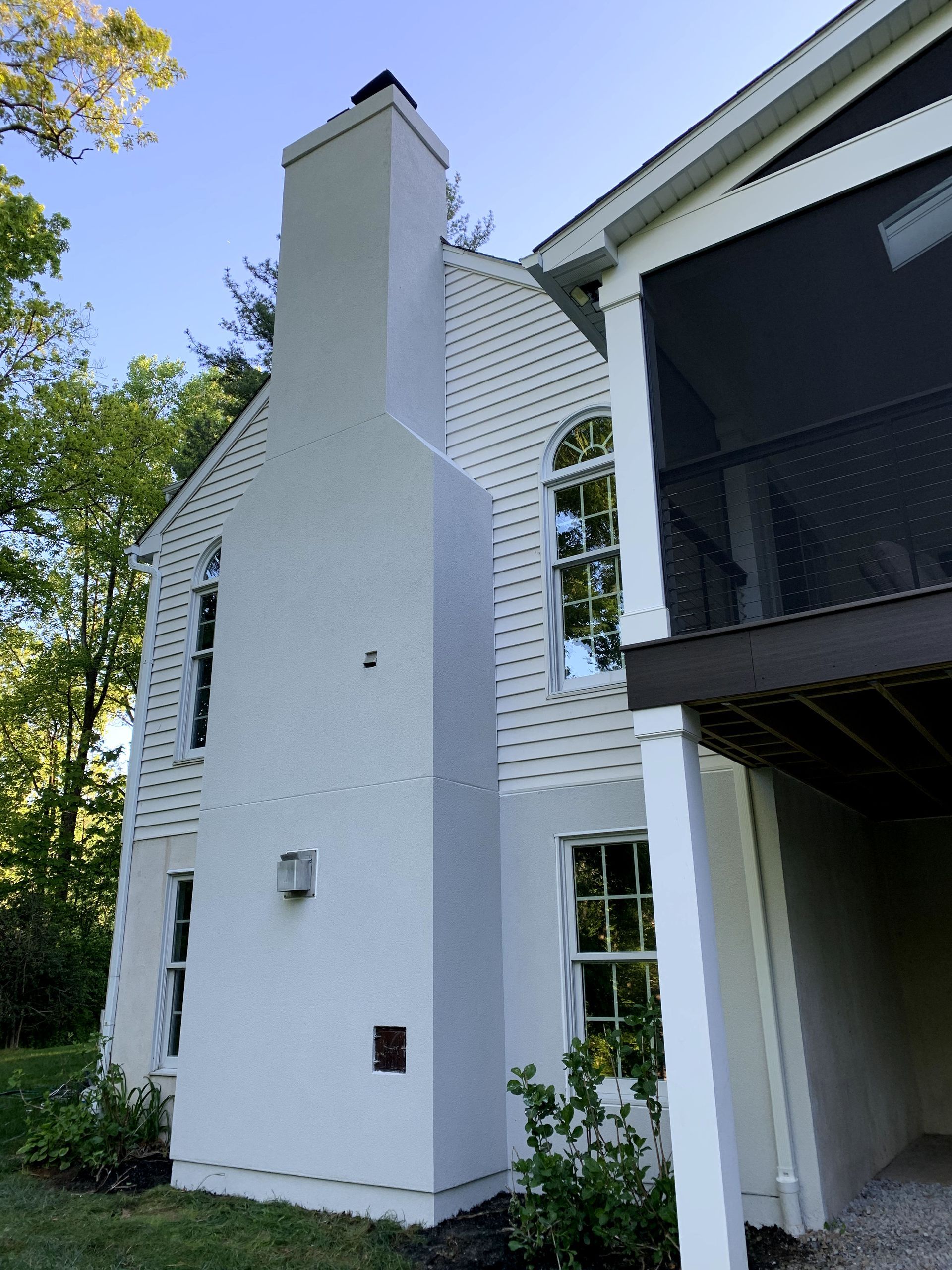 A white house with a screened in porch and a chimney