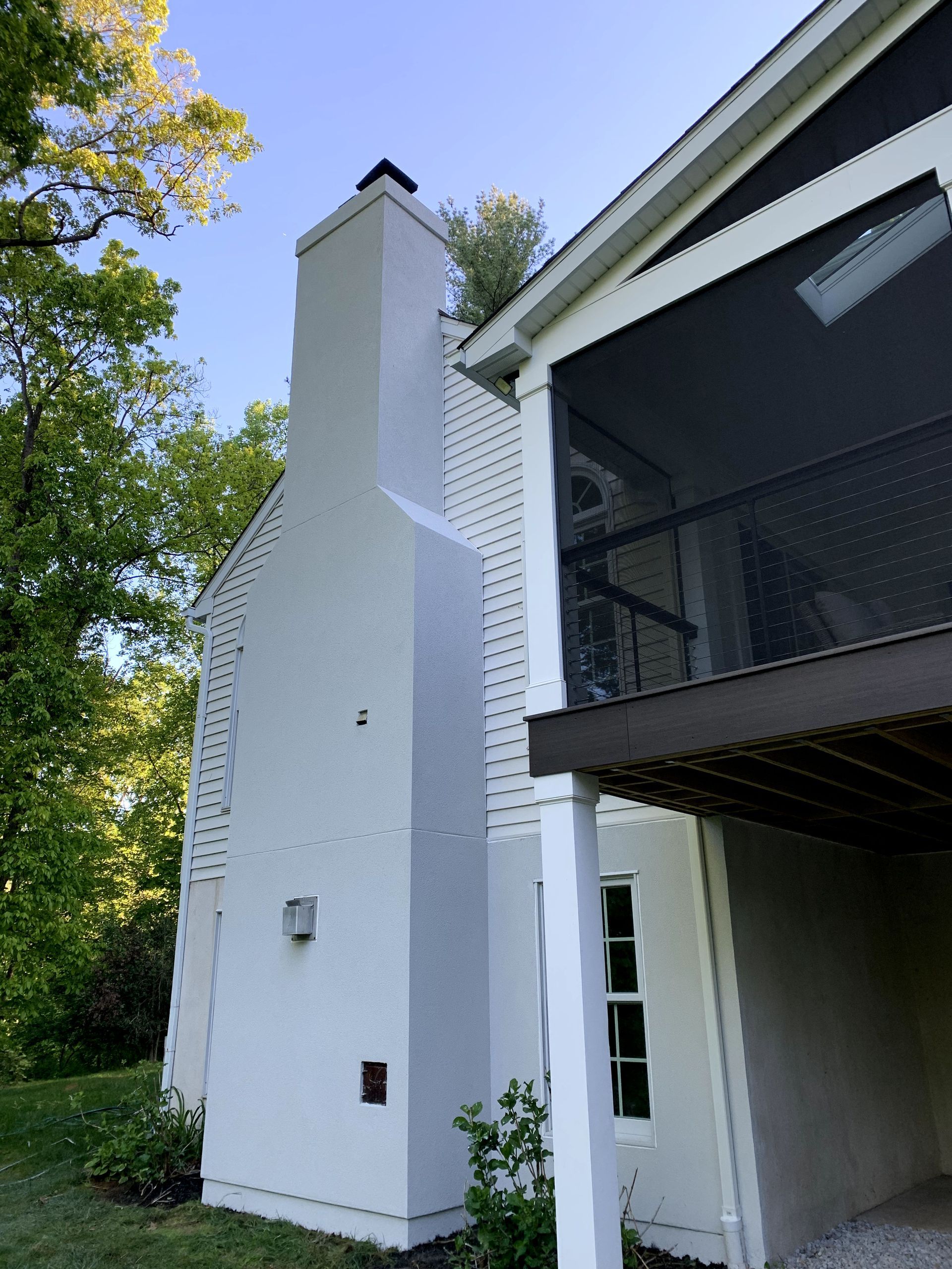 A white house with a screened in porch and a chimney