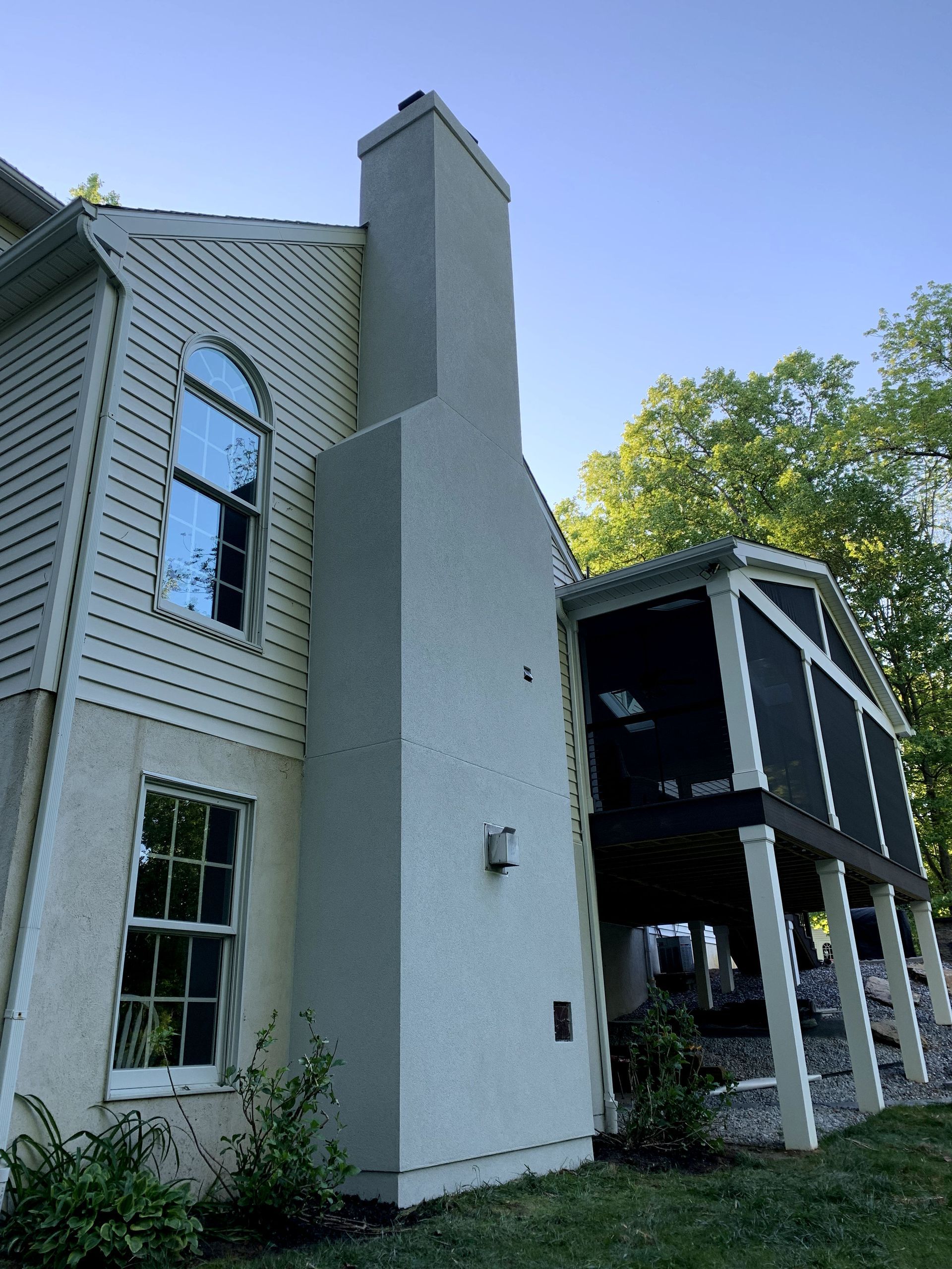A white house with a chimney and a screened in porch