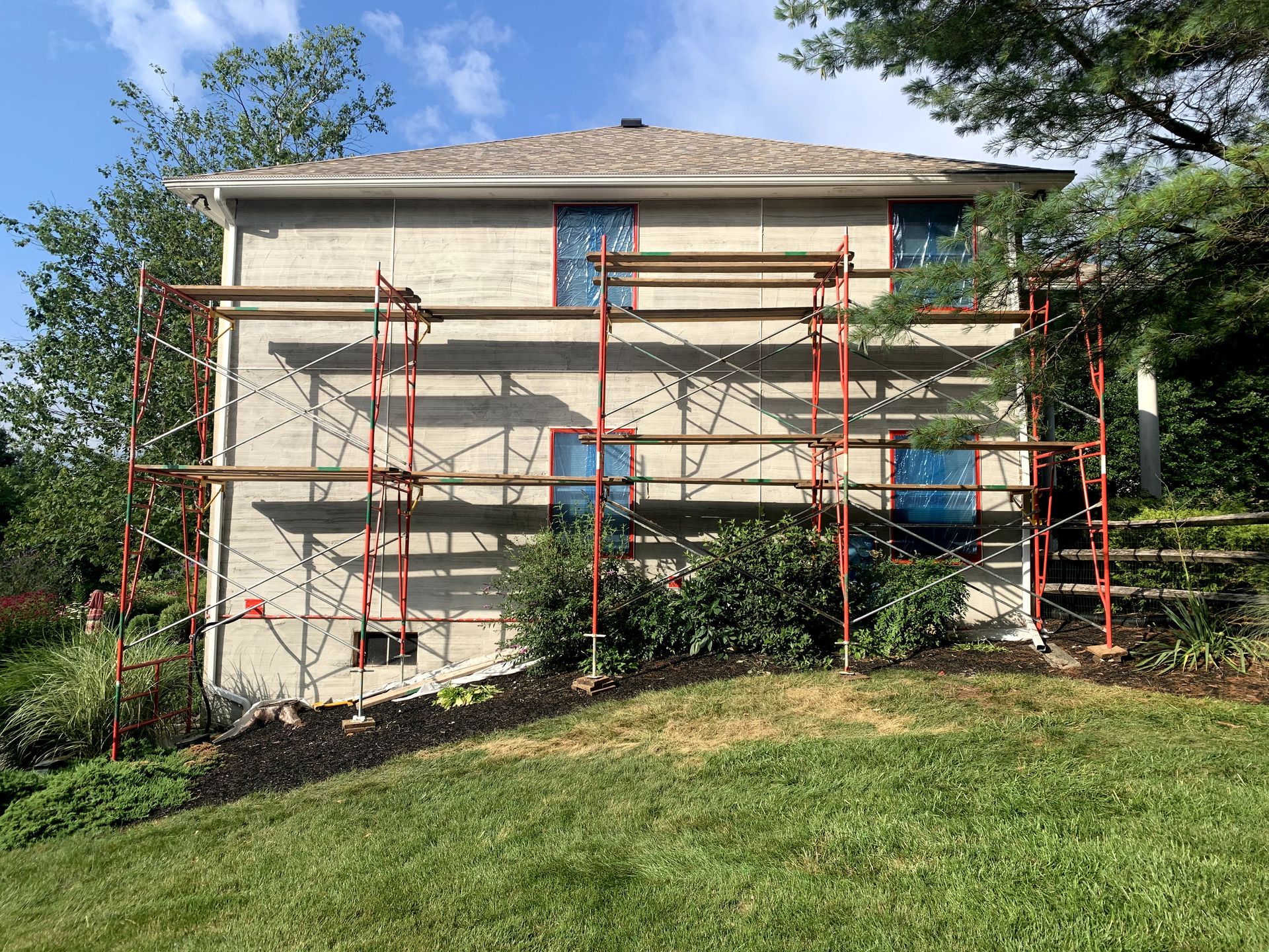 A house with scaffolding on the side of it is being painted.