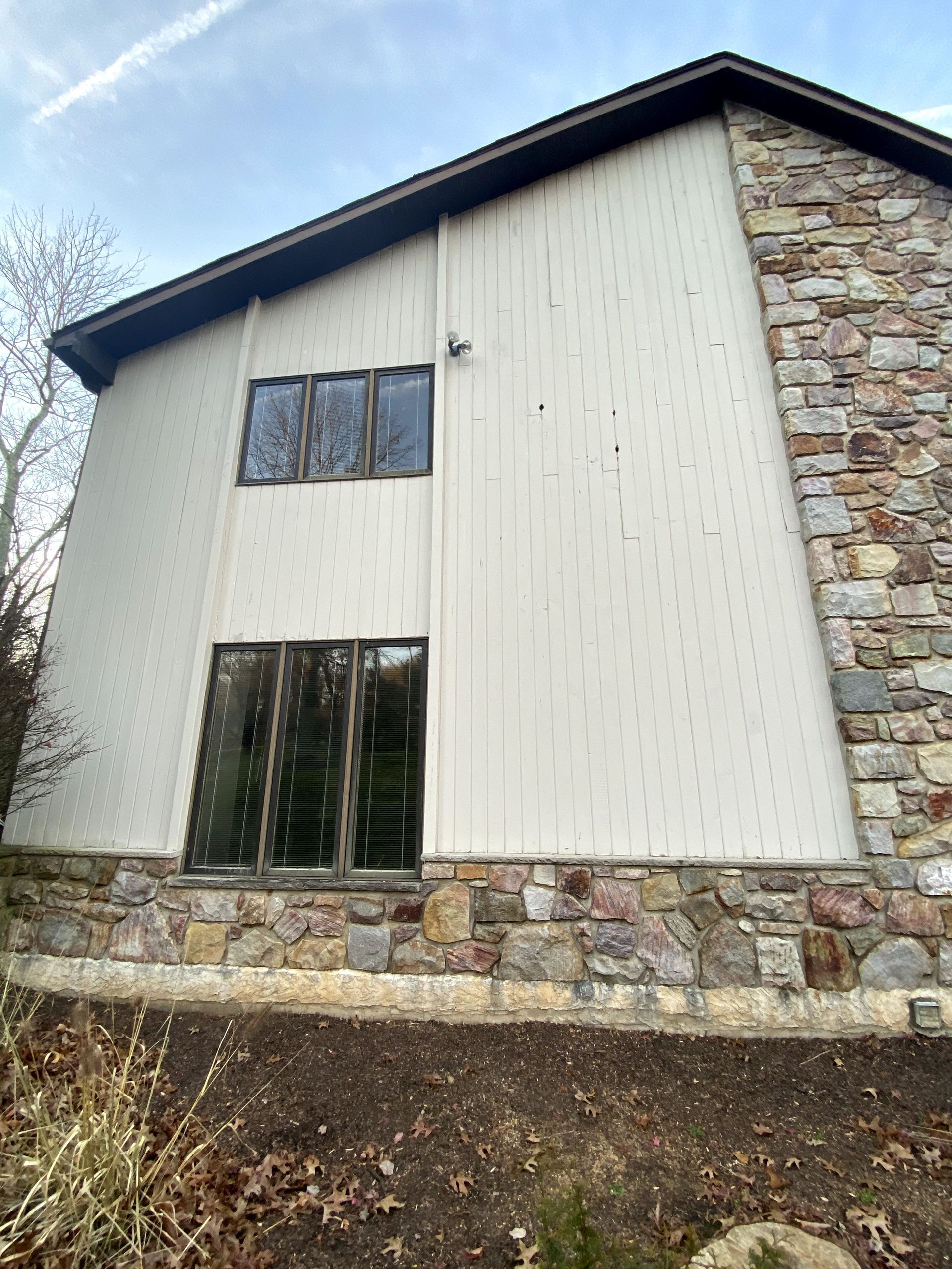 A large white house with a stone wall and a lot of windows.