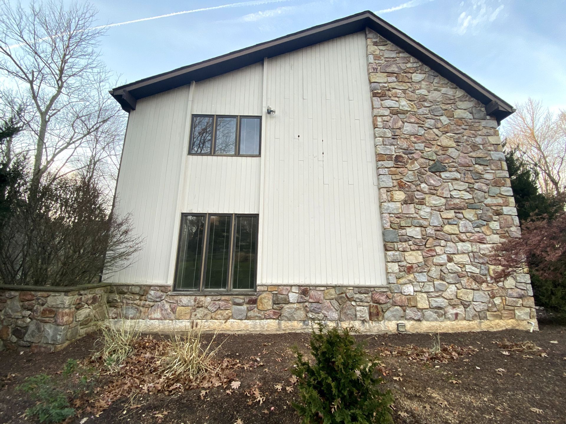 A large house with a stone facade and white siding