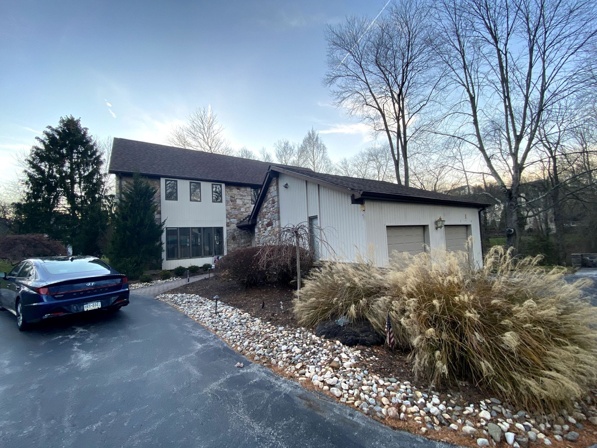 A blue car is parked in front of a large white house.