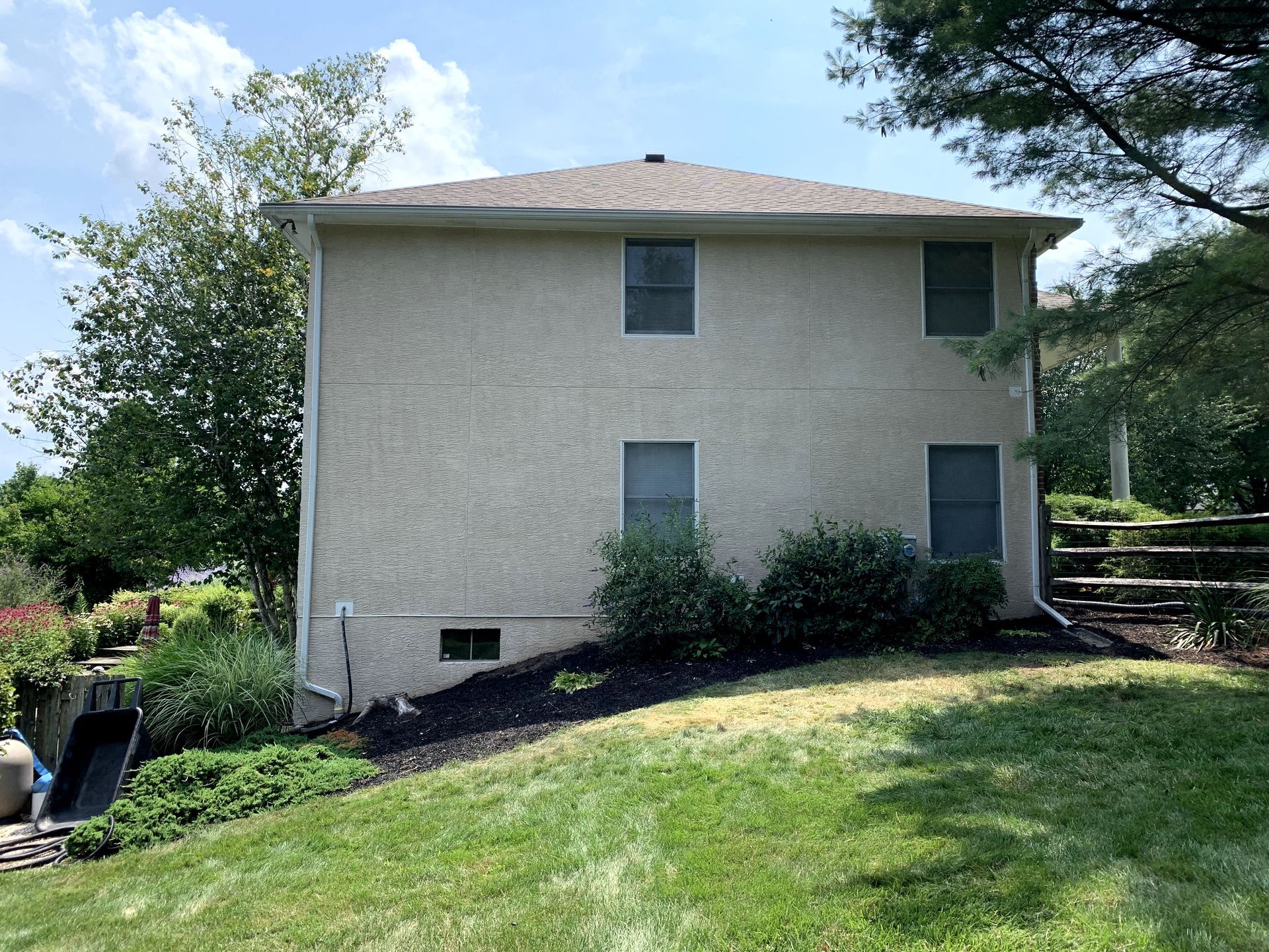 A large house with a lot of windows is sitting on top of a lush green hillside.