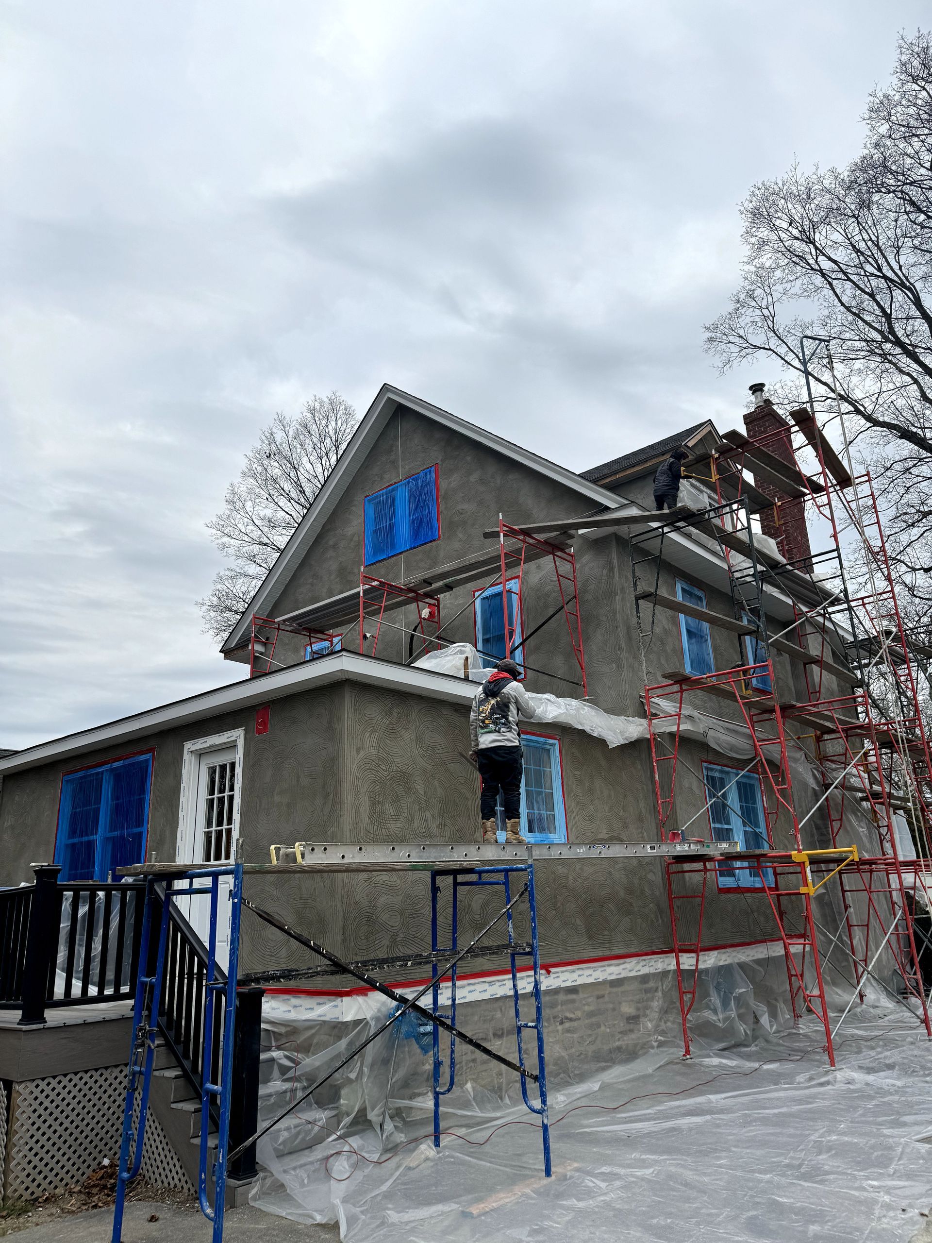 A large house is being painted with scaffolding around it.