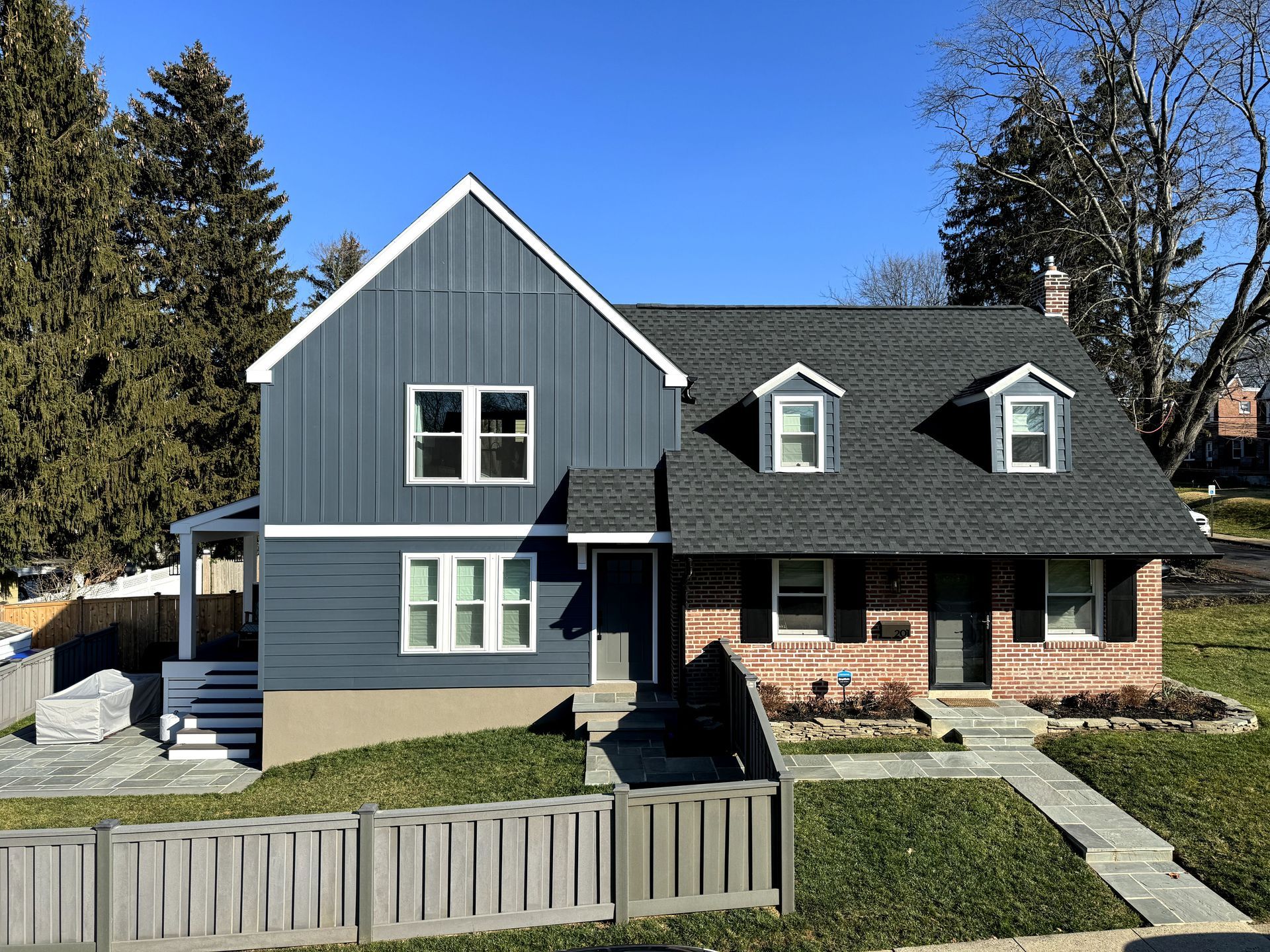 A large house with a black roof and a fence in front of it.