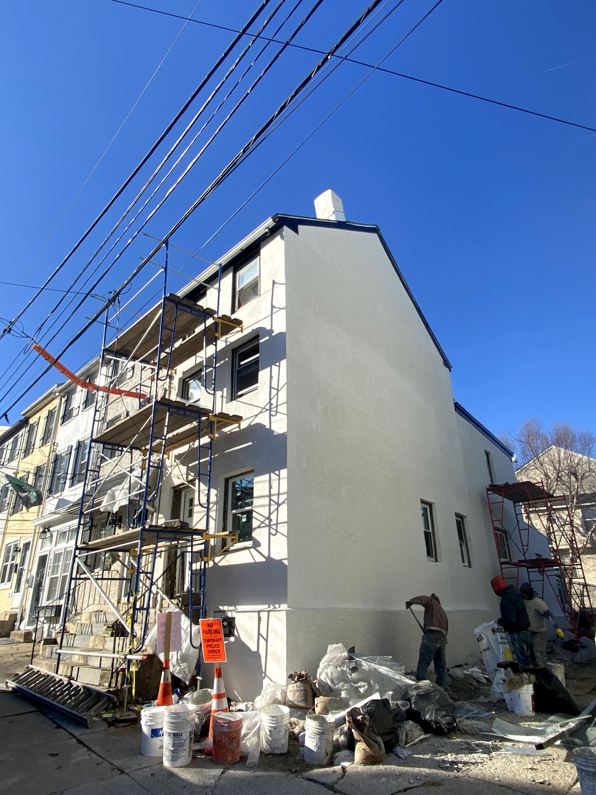 A white building is being painted with a blue sky in the background