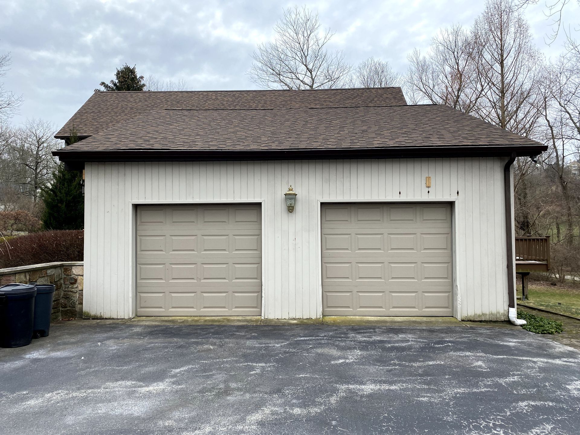 A white garage with two garage doors and a brown roof