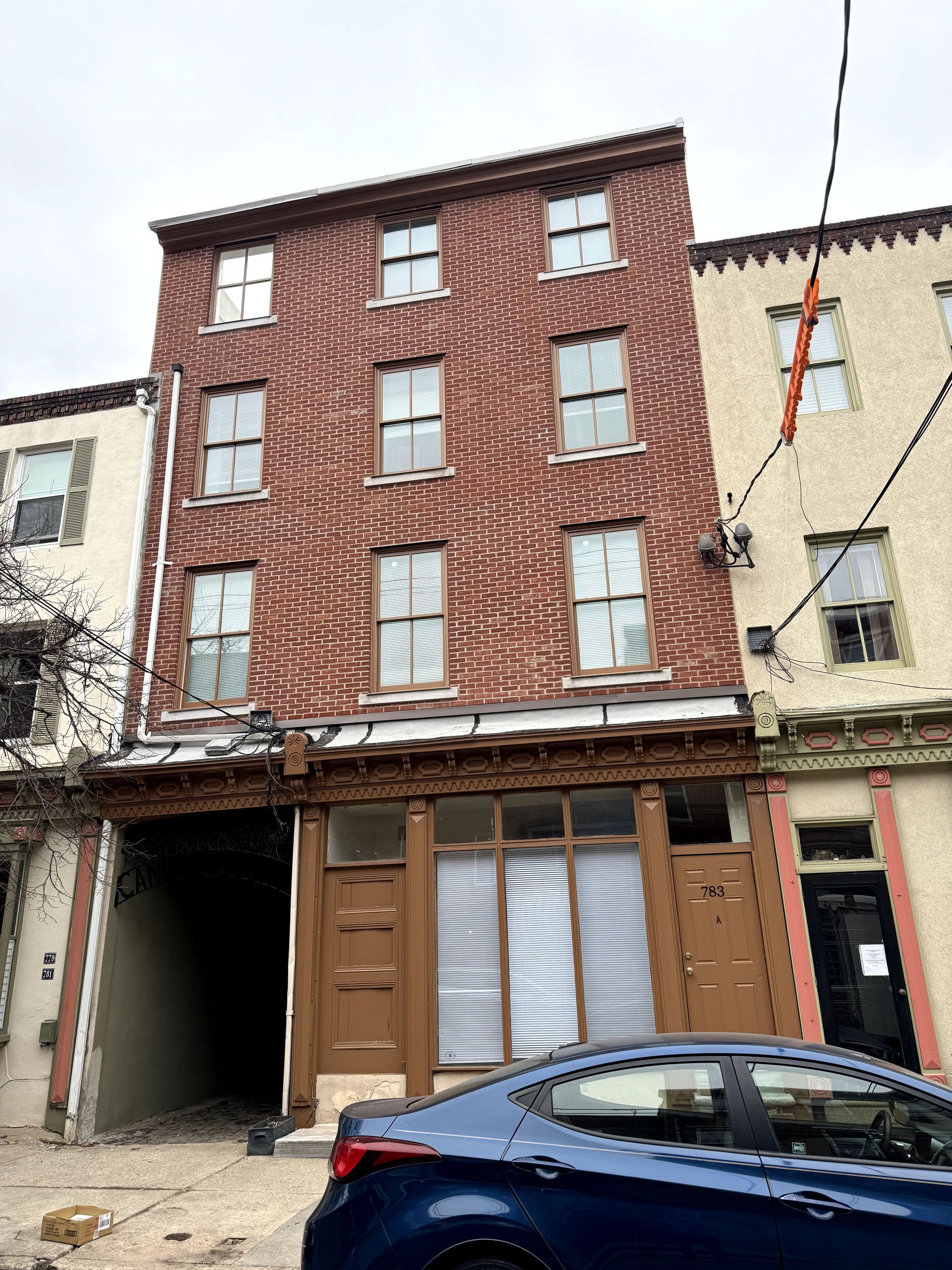 A blue car is parked in front of a brick building.