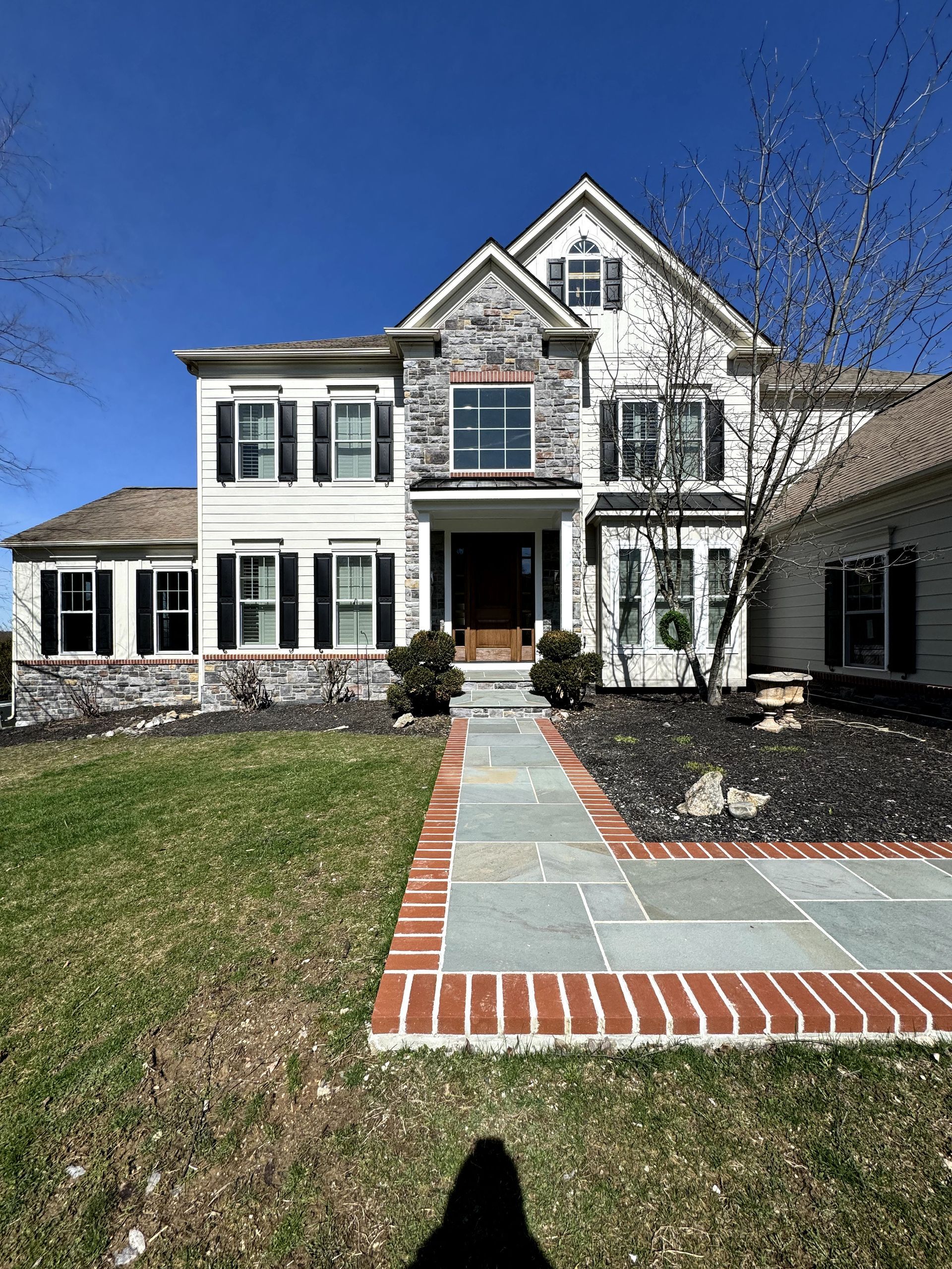 A large white house with a brick walkway leading to it.