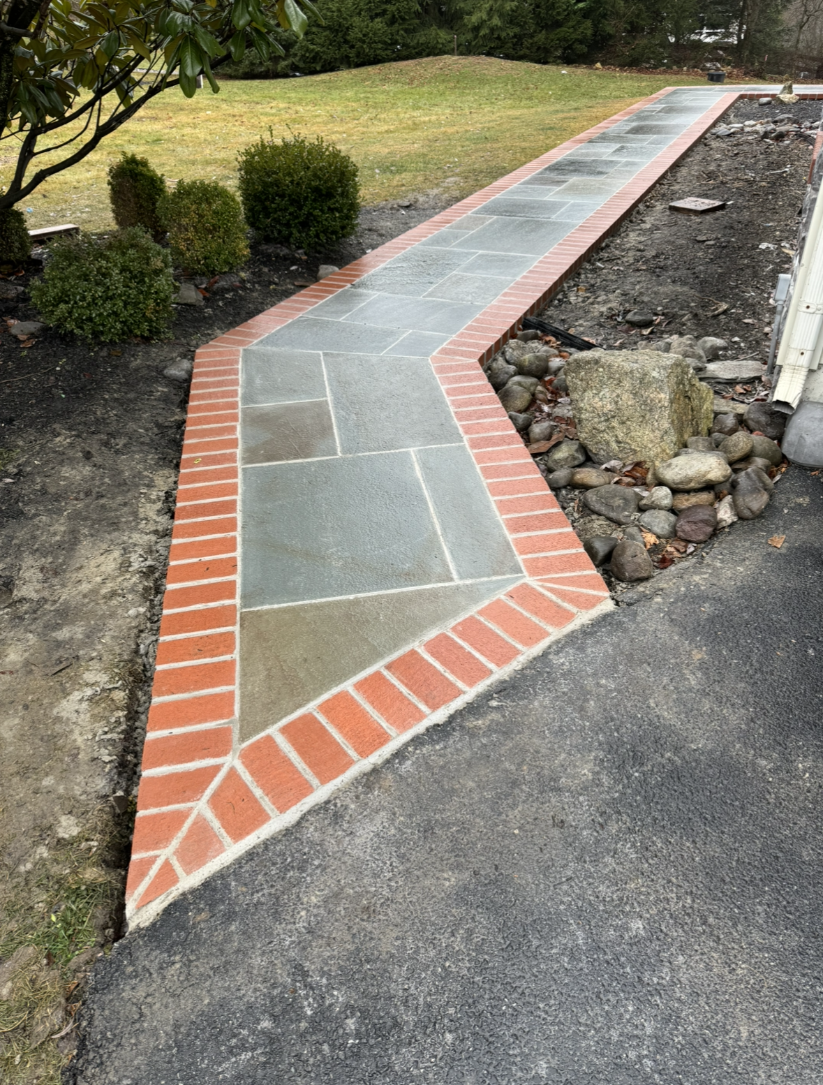 A brick and stone walkway leading to a yard.