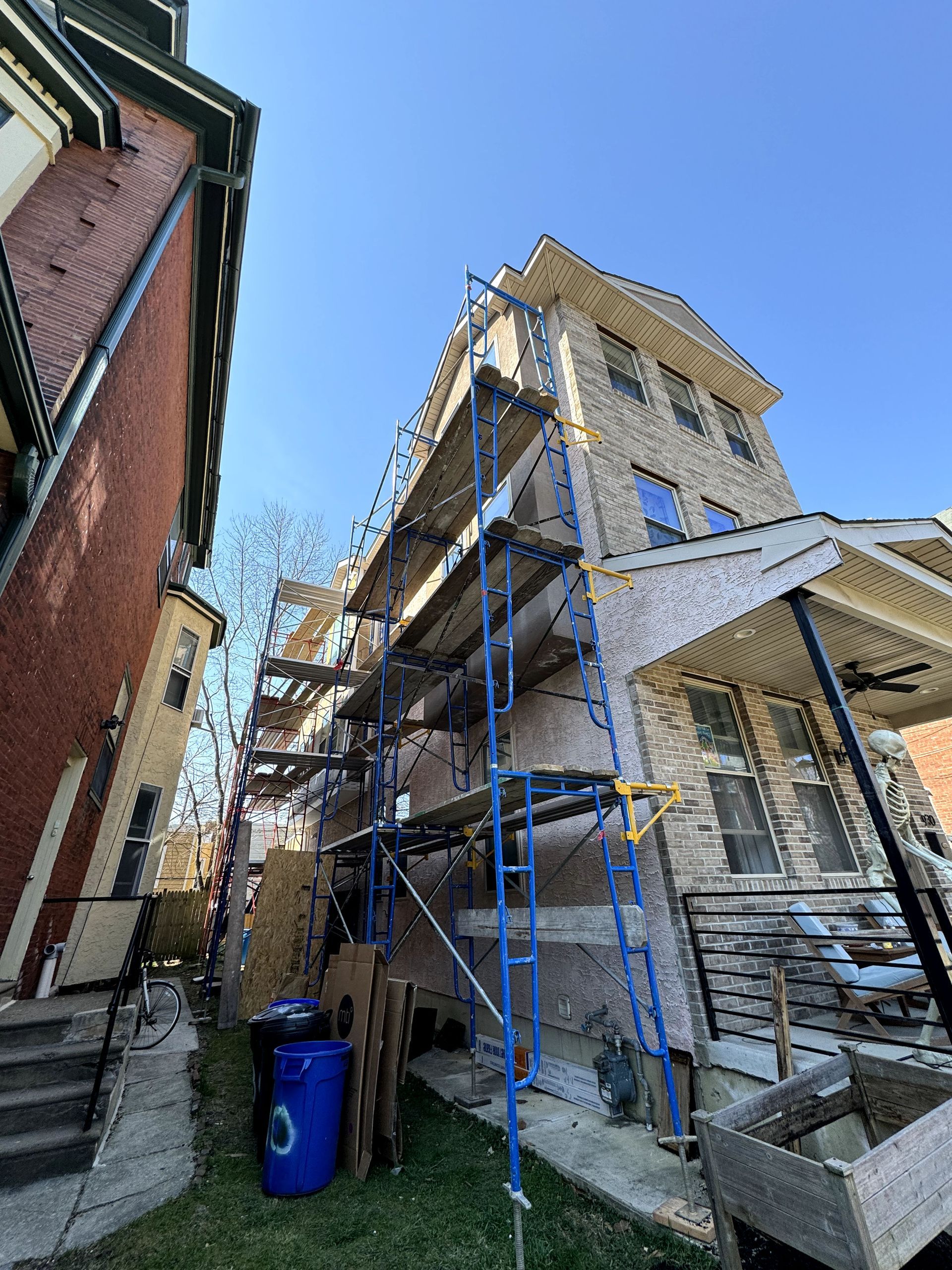 A large brick building with scaffolding around it is being painted.