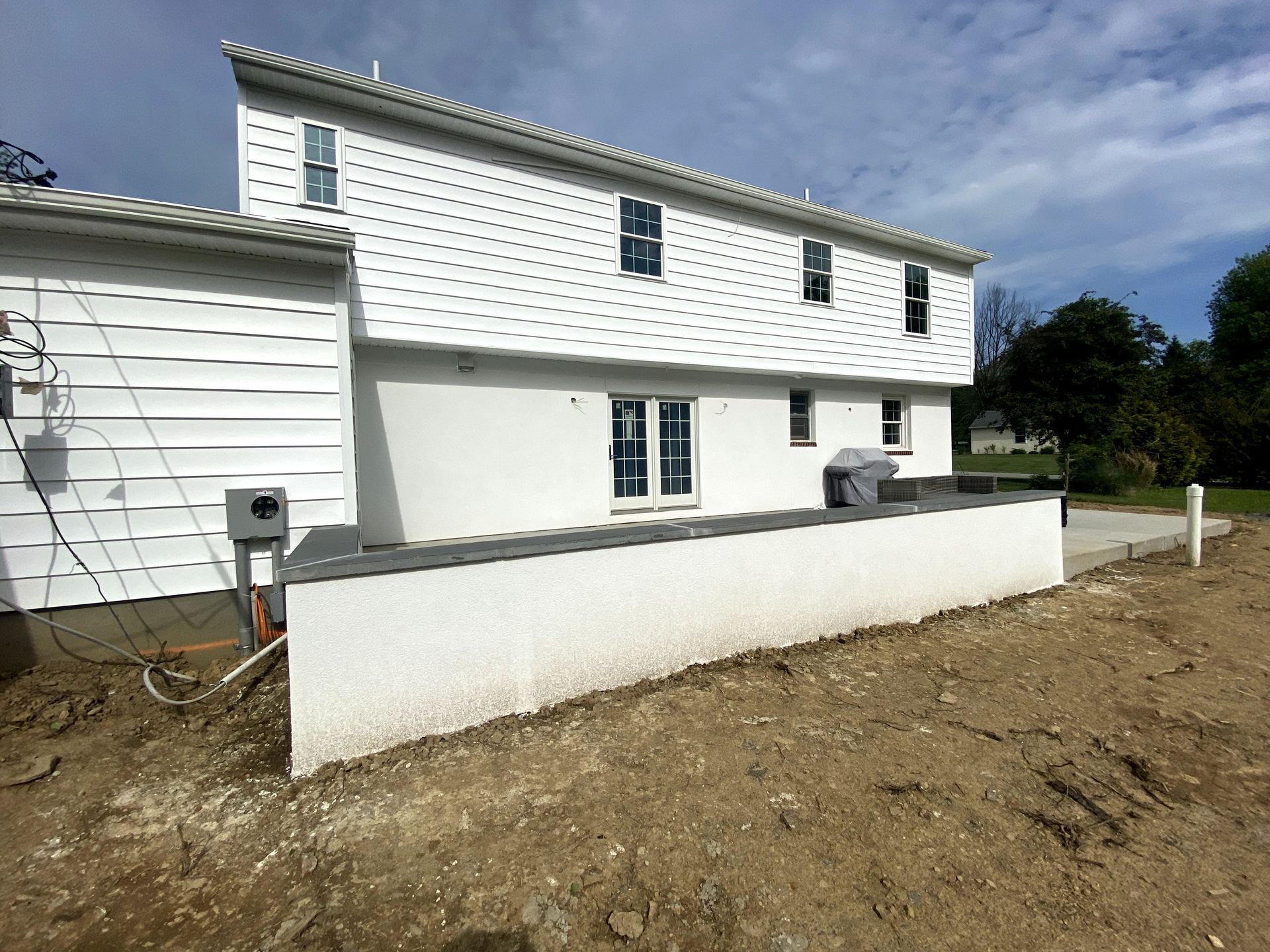 A large white house is sitting in the middle of a dirt field.