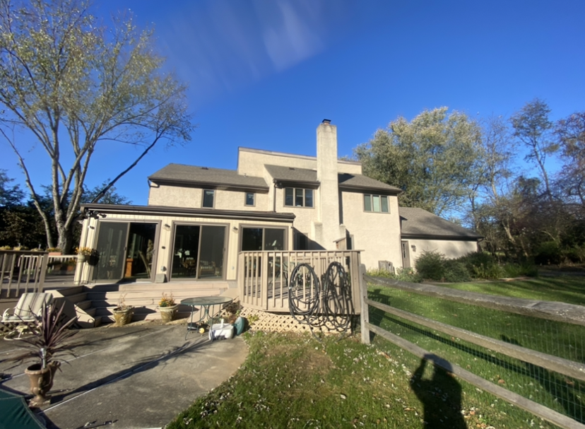 A large house with a deck and a fence in front of it