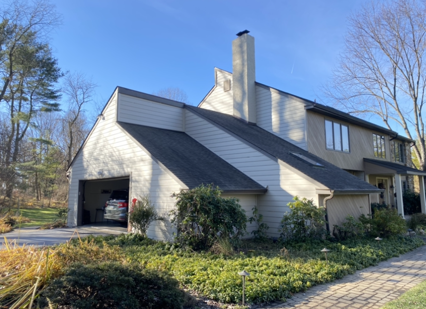 A large white house with a car parked in the garage.