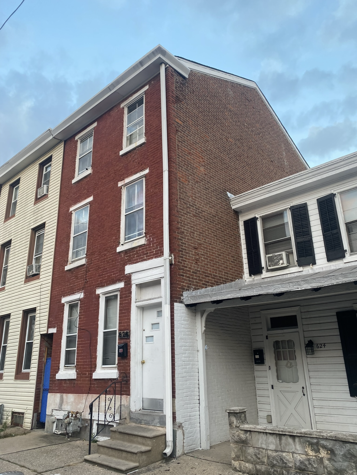 A red brick building with a white house in front of it.