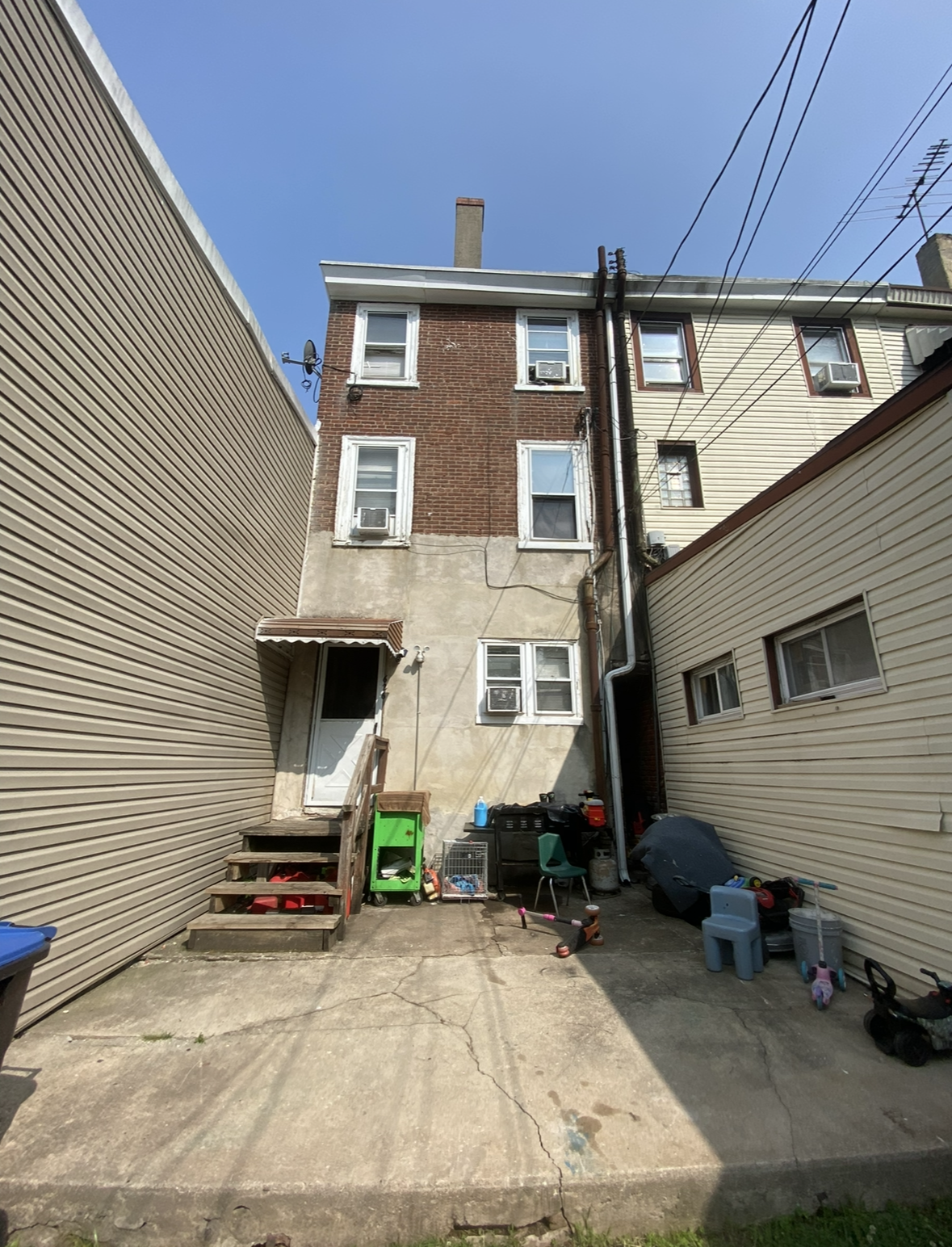 The backyard of a house with a brick building and a concrete patio.