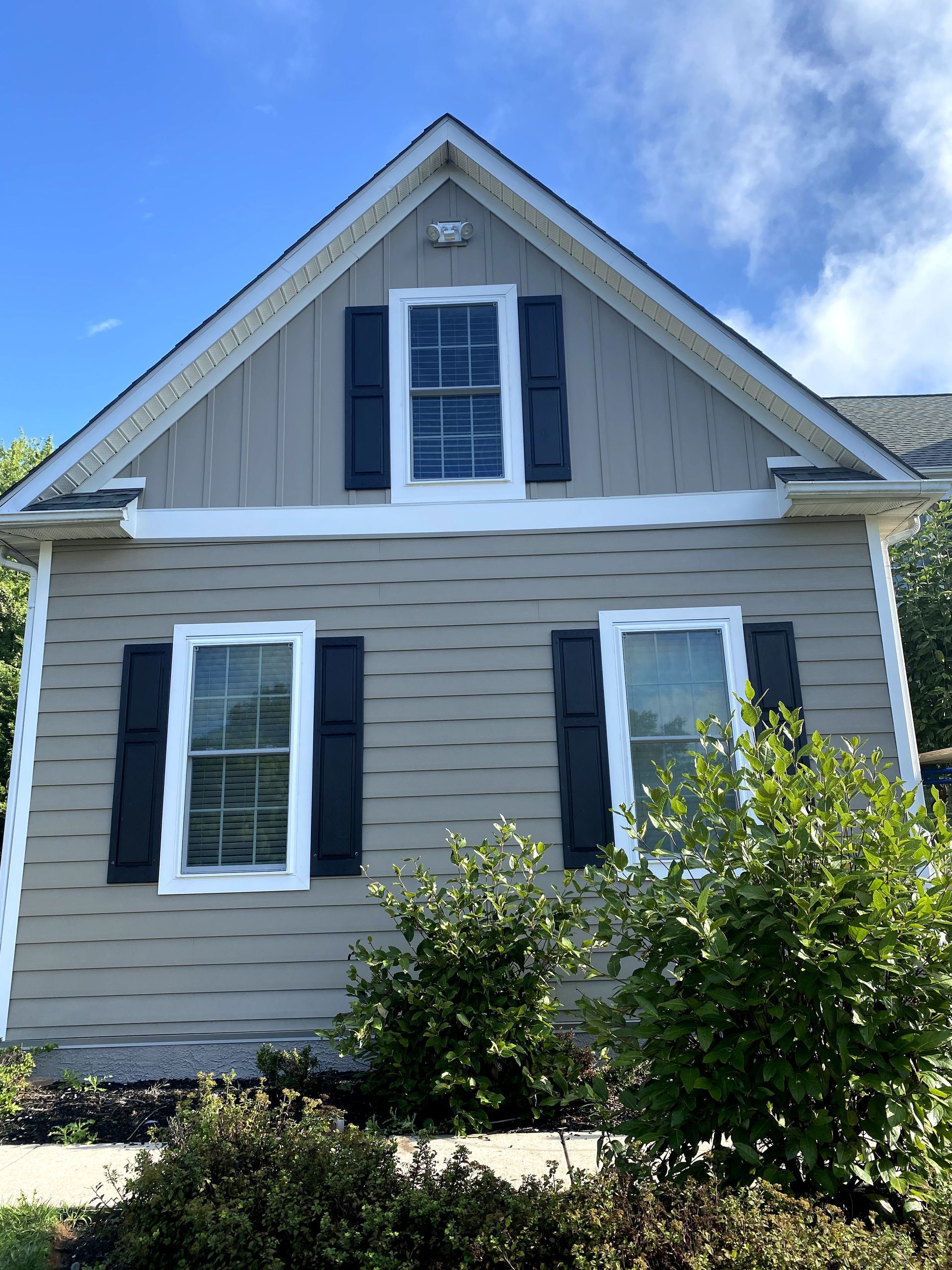 A house with black shutters and a blue sky in the background