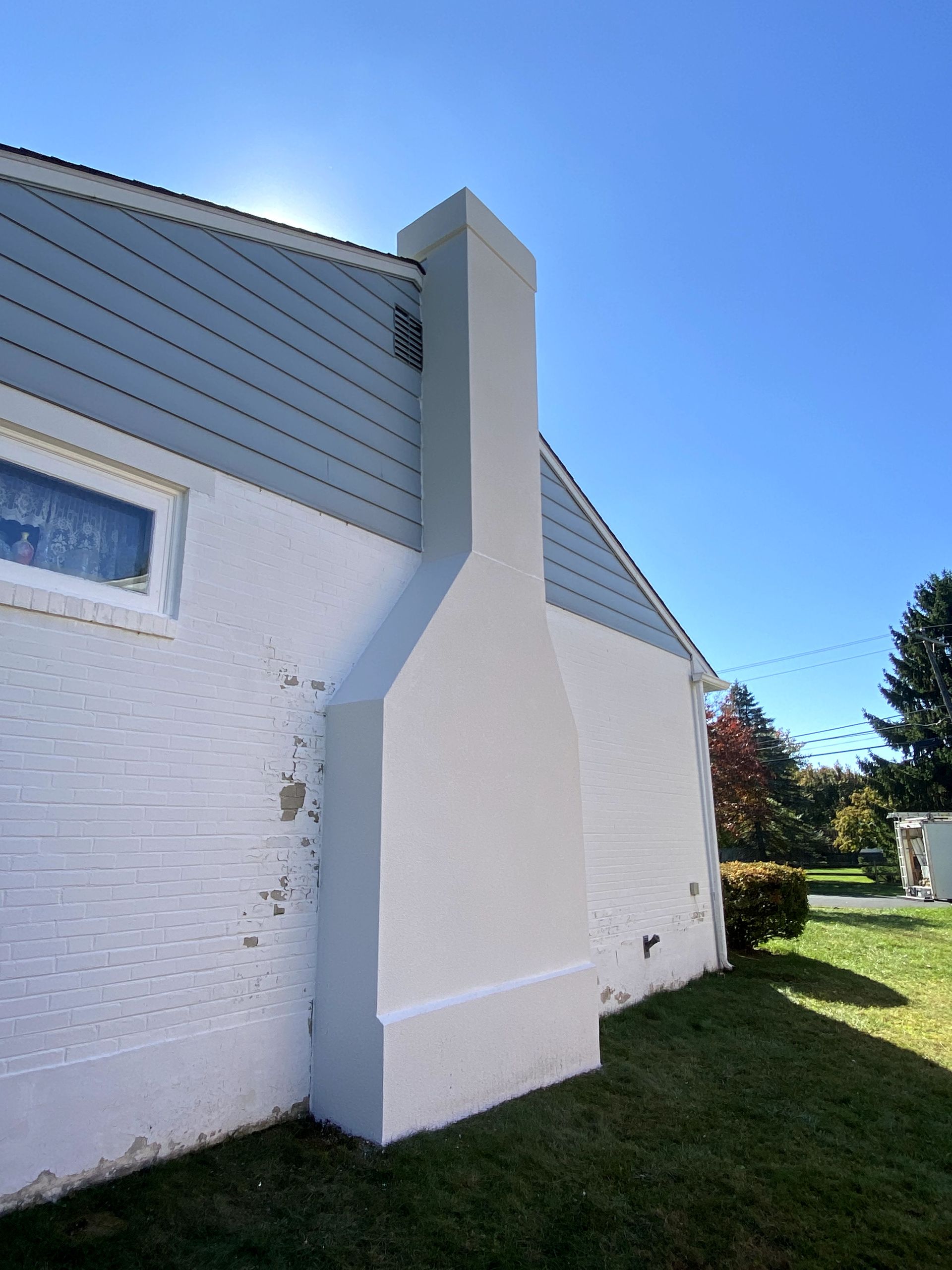 A white house with a large chimney on the side