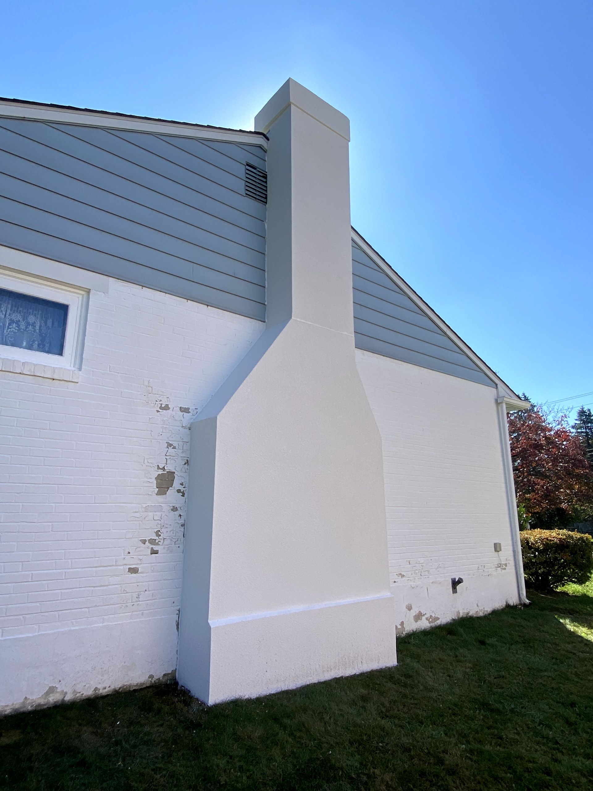 A white house with a chimney on the side of it