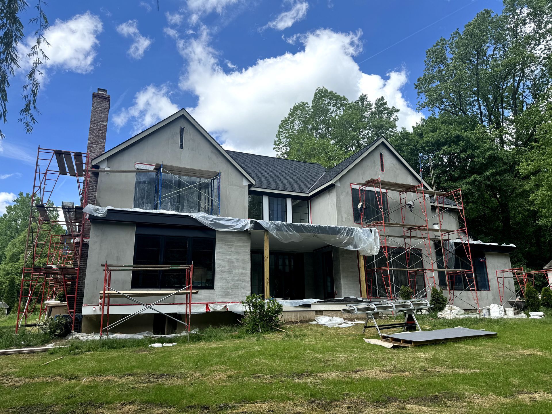 A large house is being built in the middle of a lush green field.