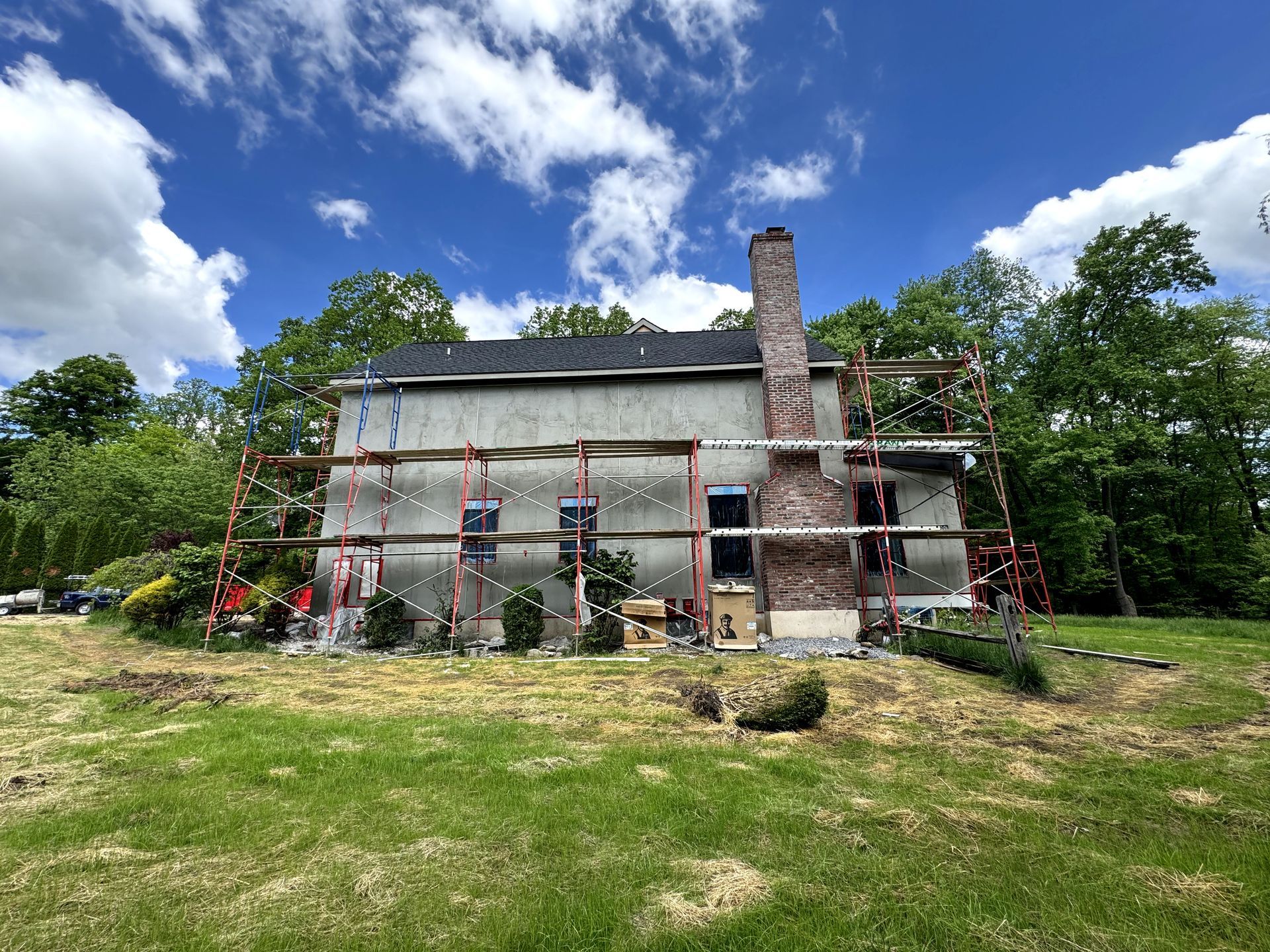 A large house is being built in a grassy field with scaffolding around it.