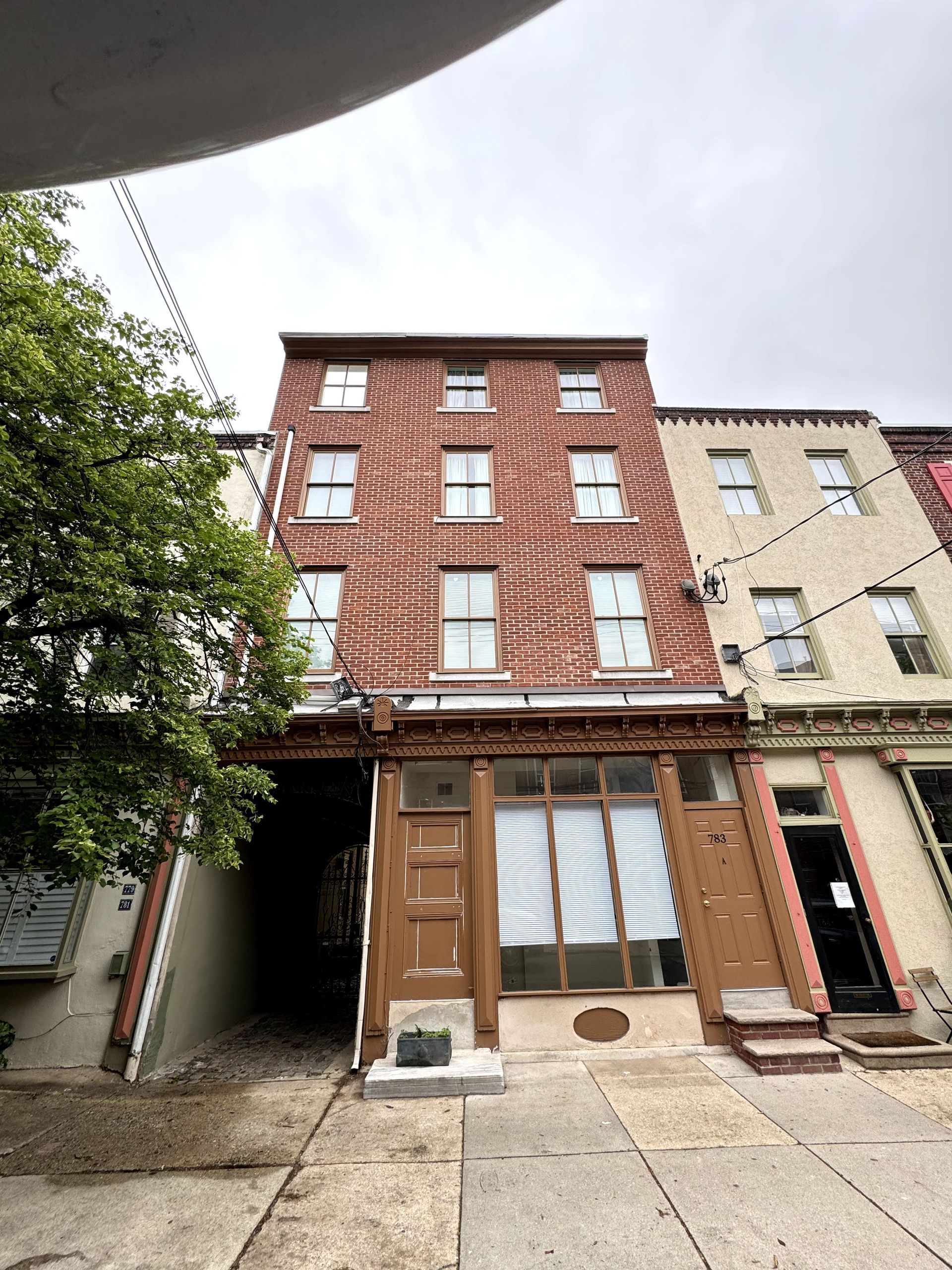 A large brick building with a lot of windows and a tree in front of it.