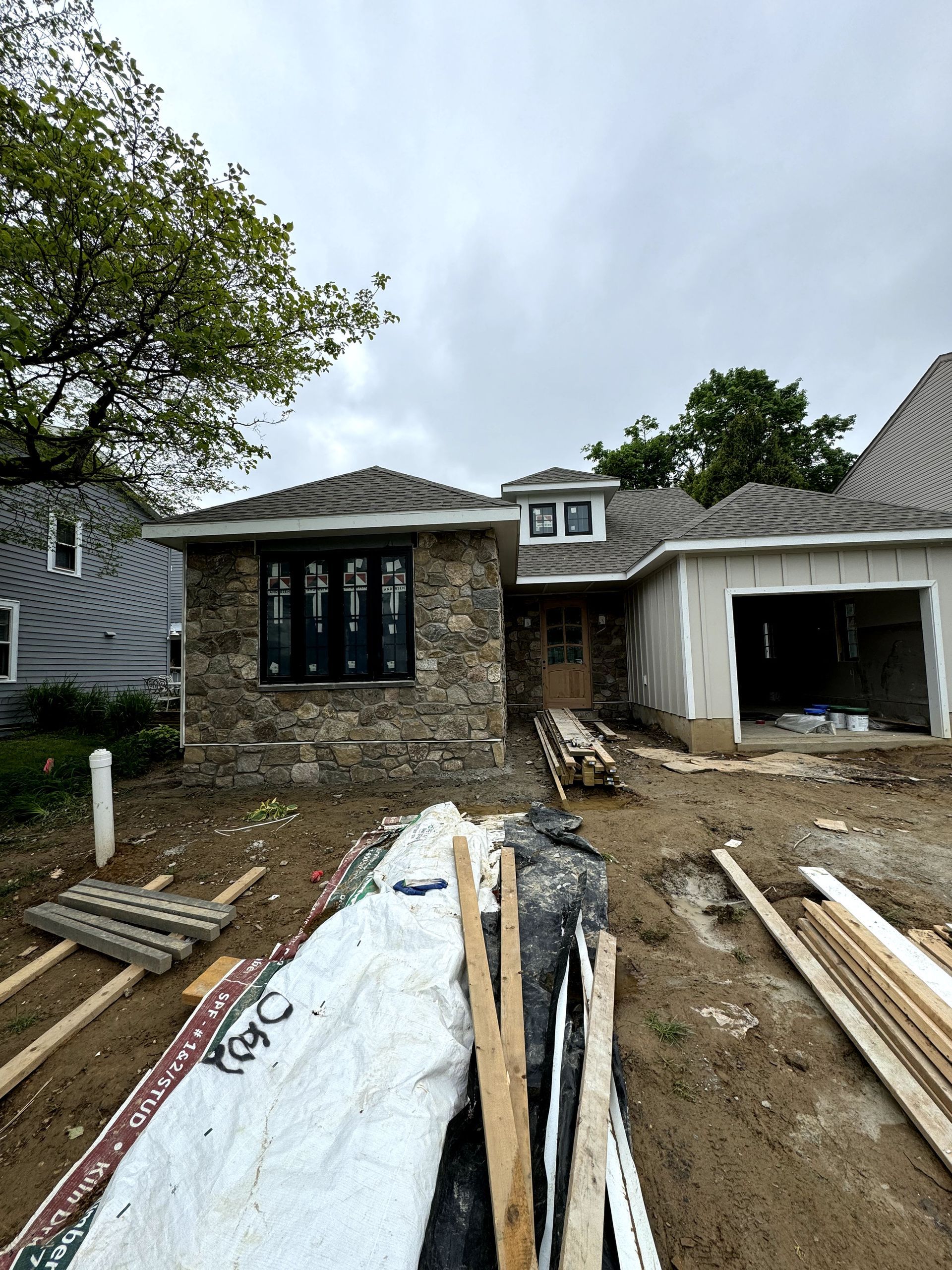 A house under construction with a lot of wood in front of it.