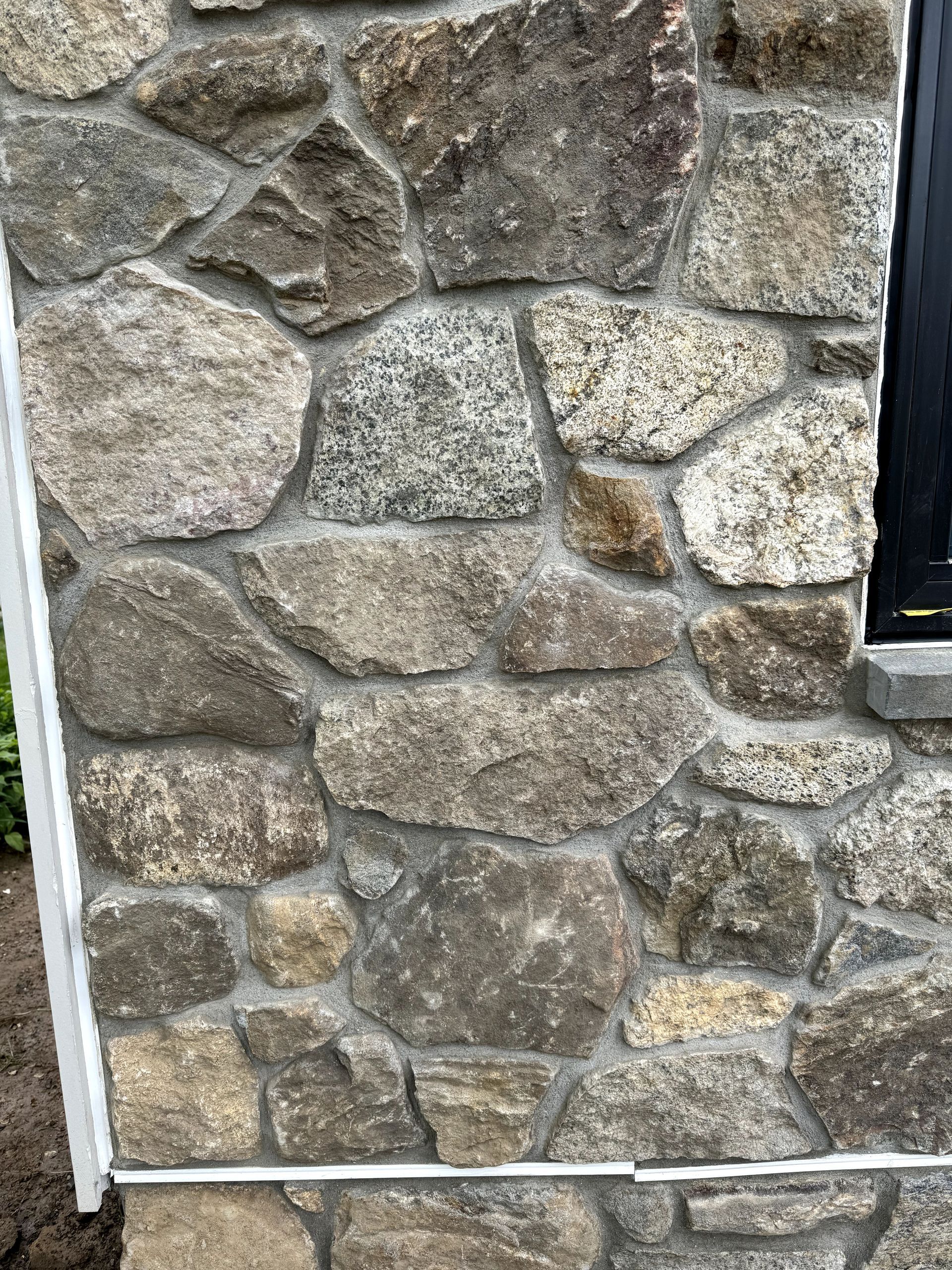 A close up of a stone wall with a window.
