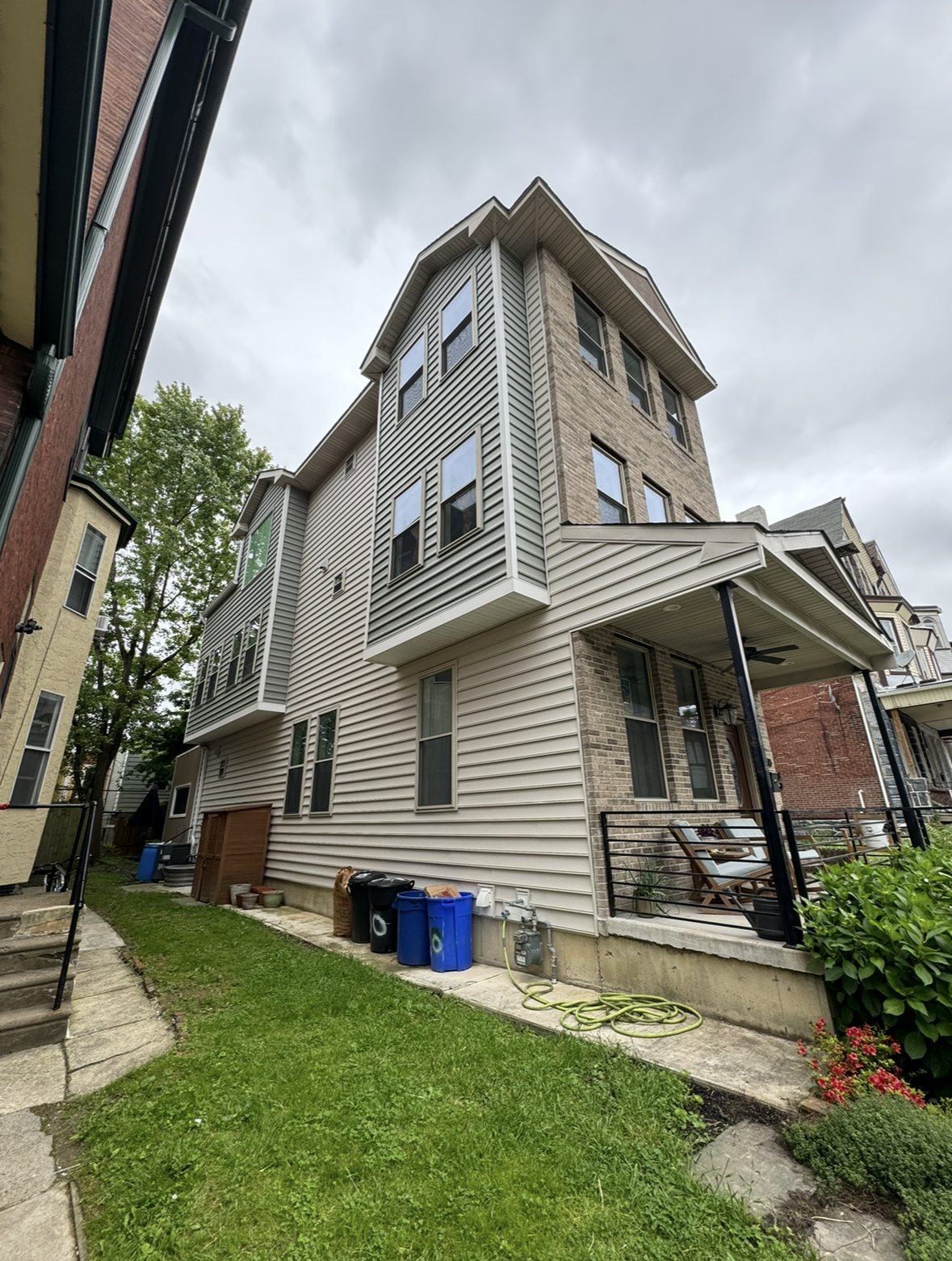 A large house with a porch and a lot of trash cans in front of it.