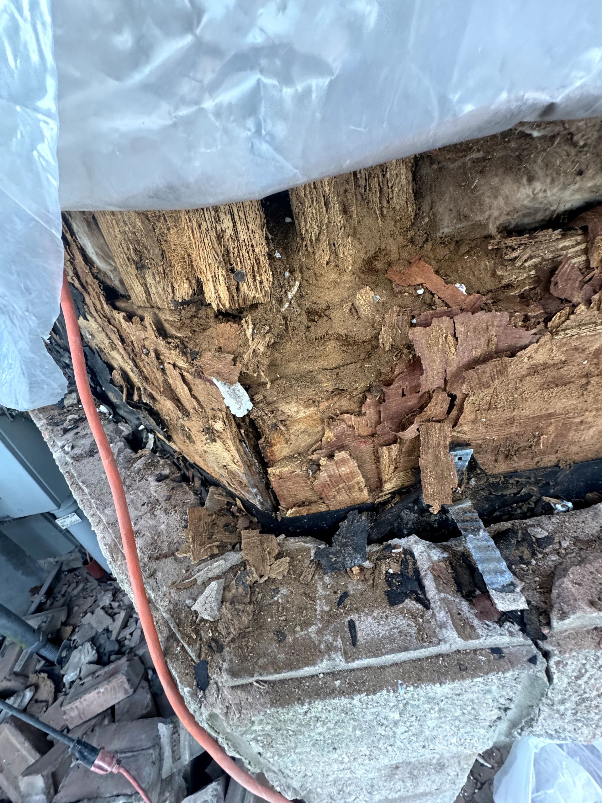 A piece of wood is sitting on top of a pile of bricks next to a power cord.