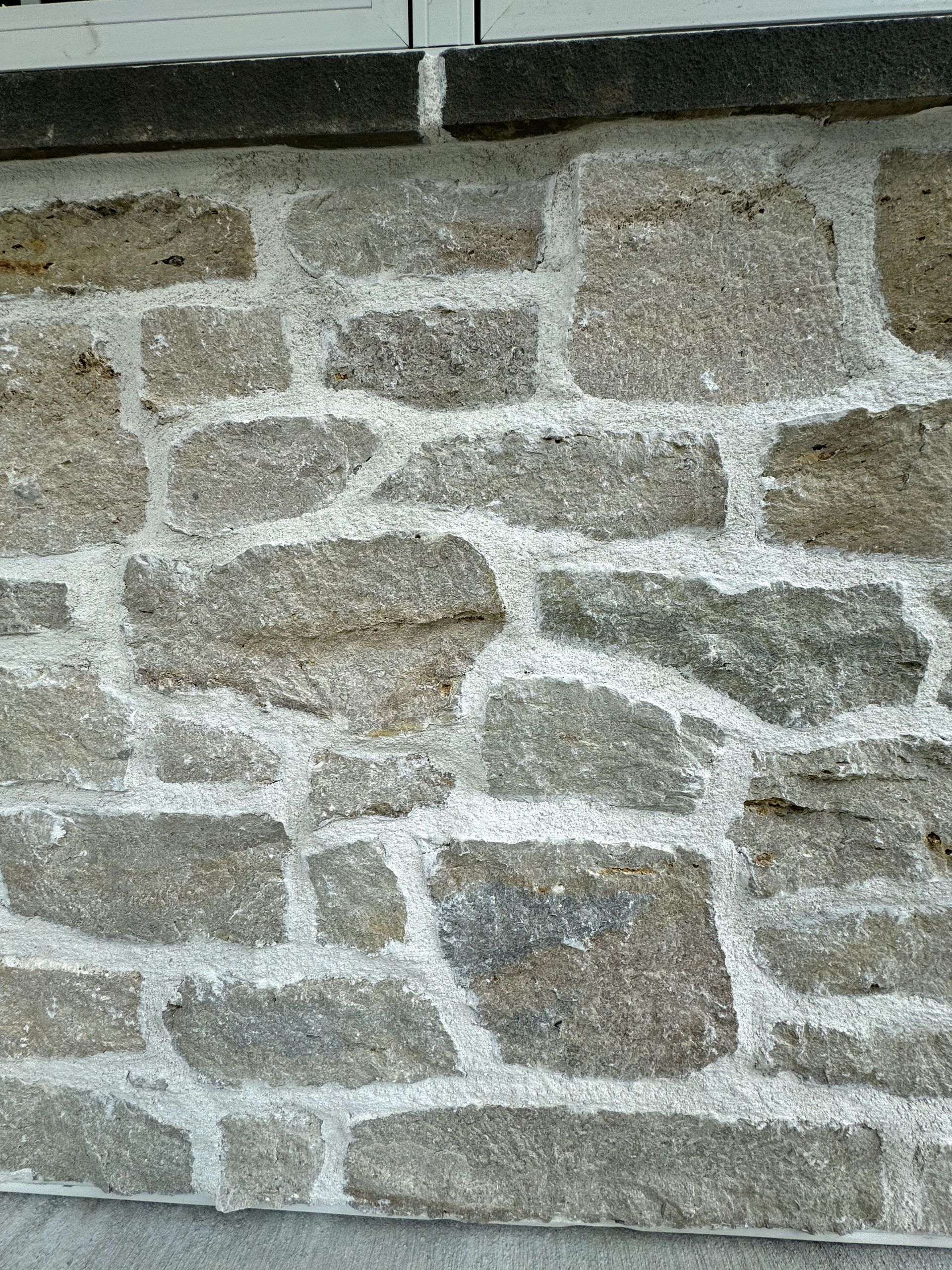 A close up of a stone wall with white paint on it