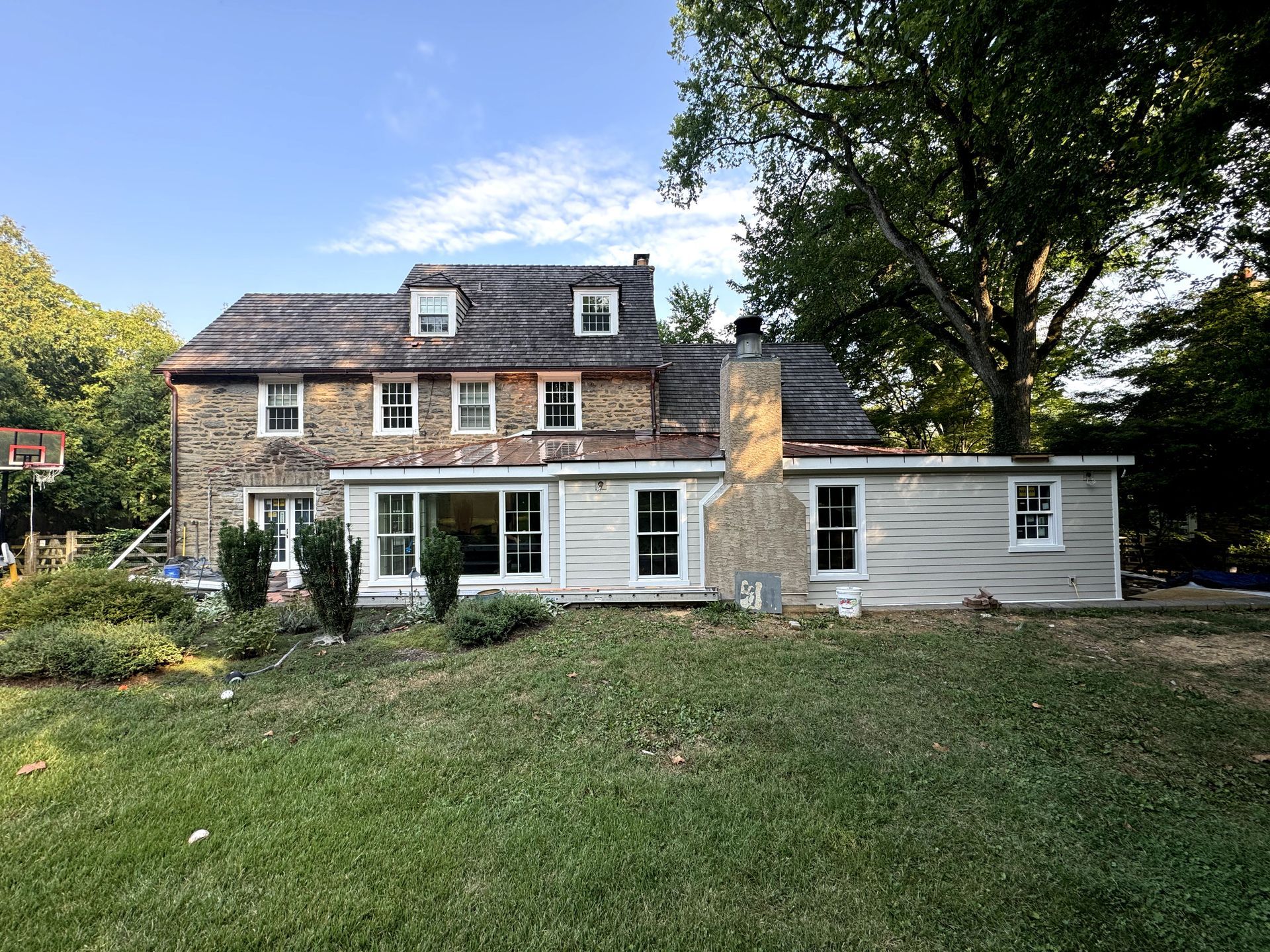 A large house with a lot of windows and a basketball hoop in the backyard.