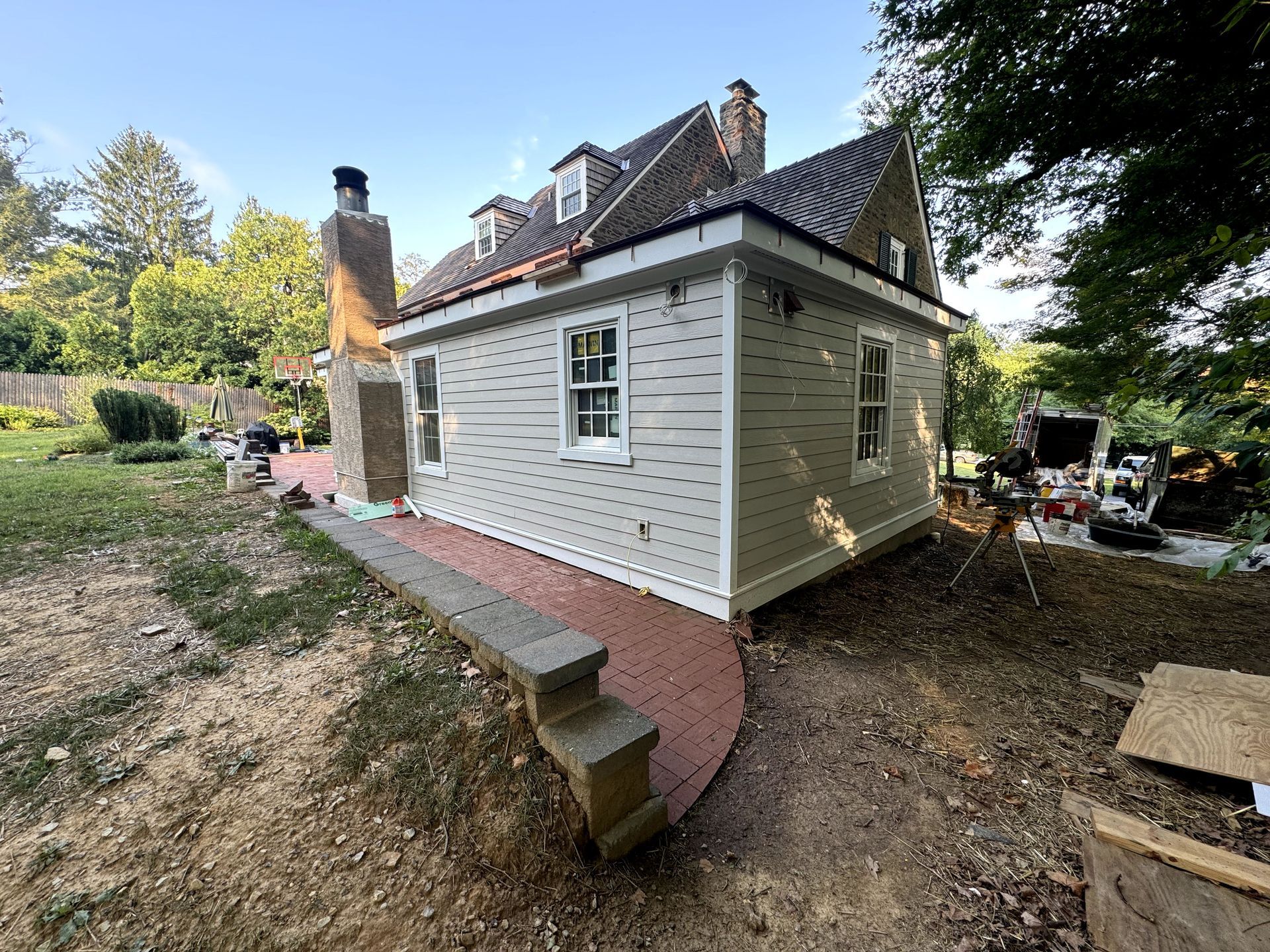 A house with a brick walkway leading to it is being remodeled.