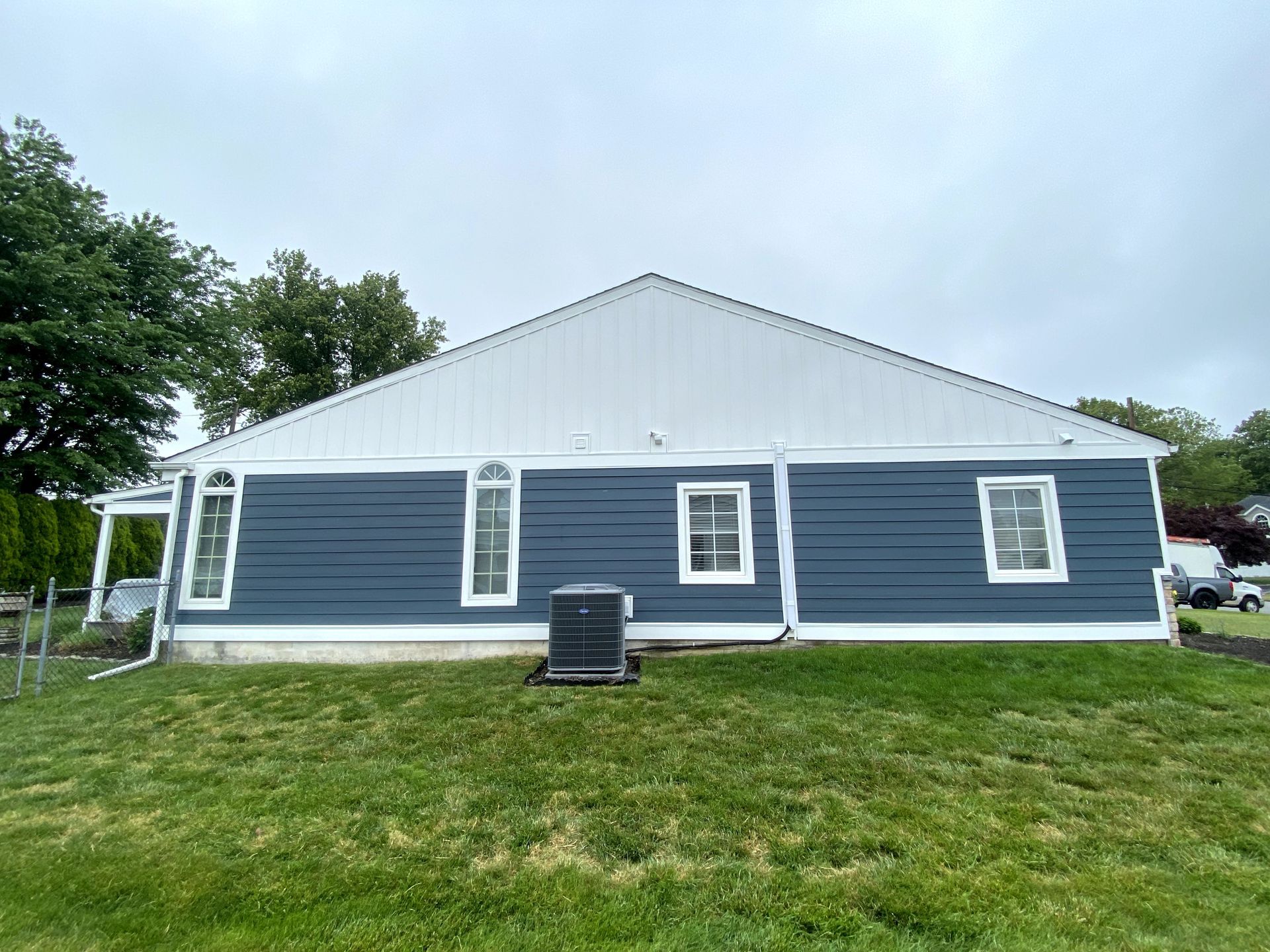 A blue house with a white roof is sitting on top of a lush green field.