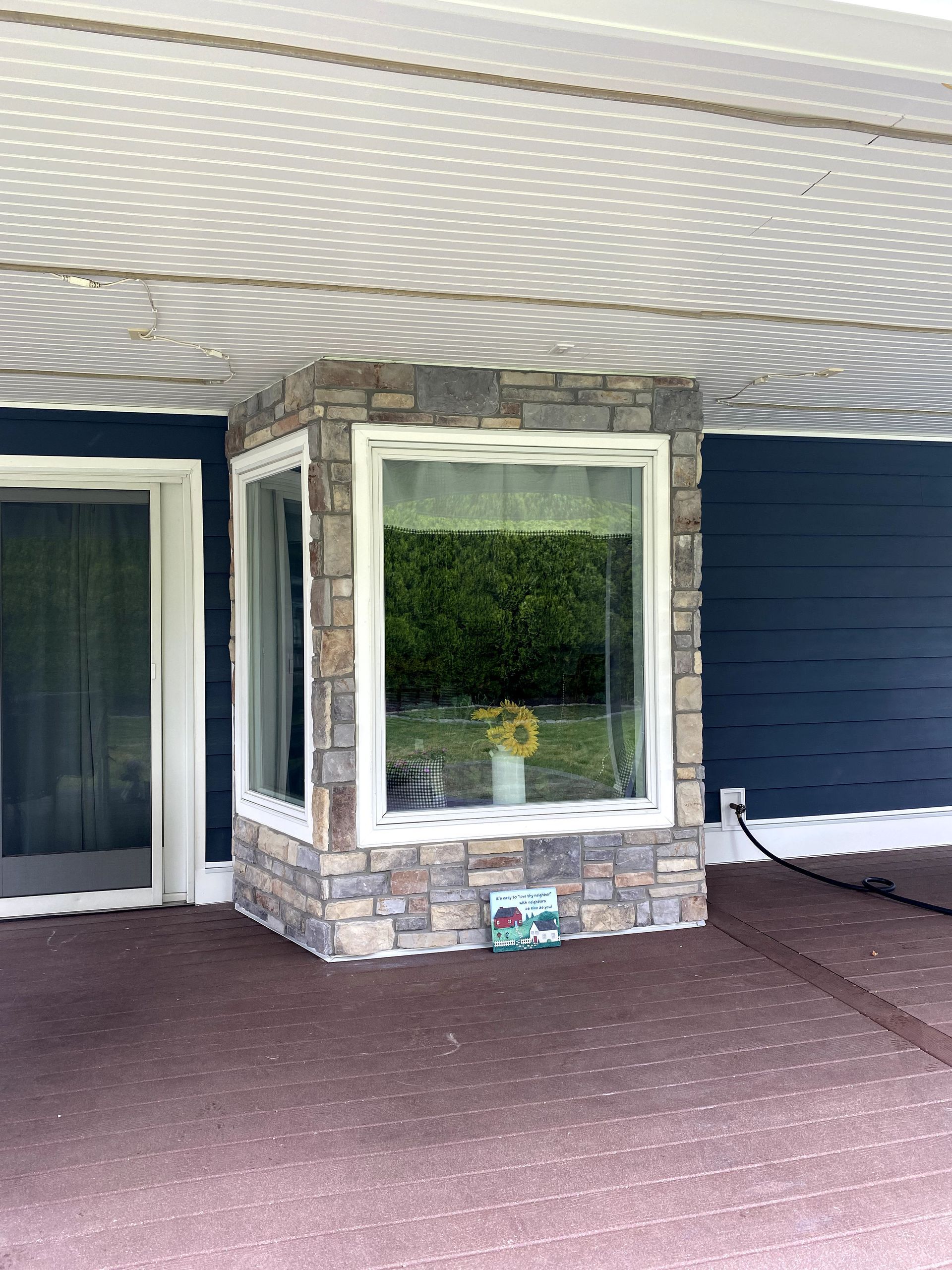 There is a window on the side of the house with a sunflower in it.