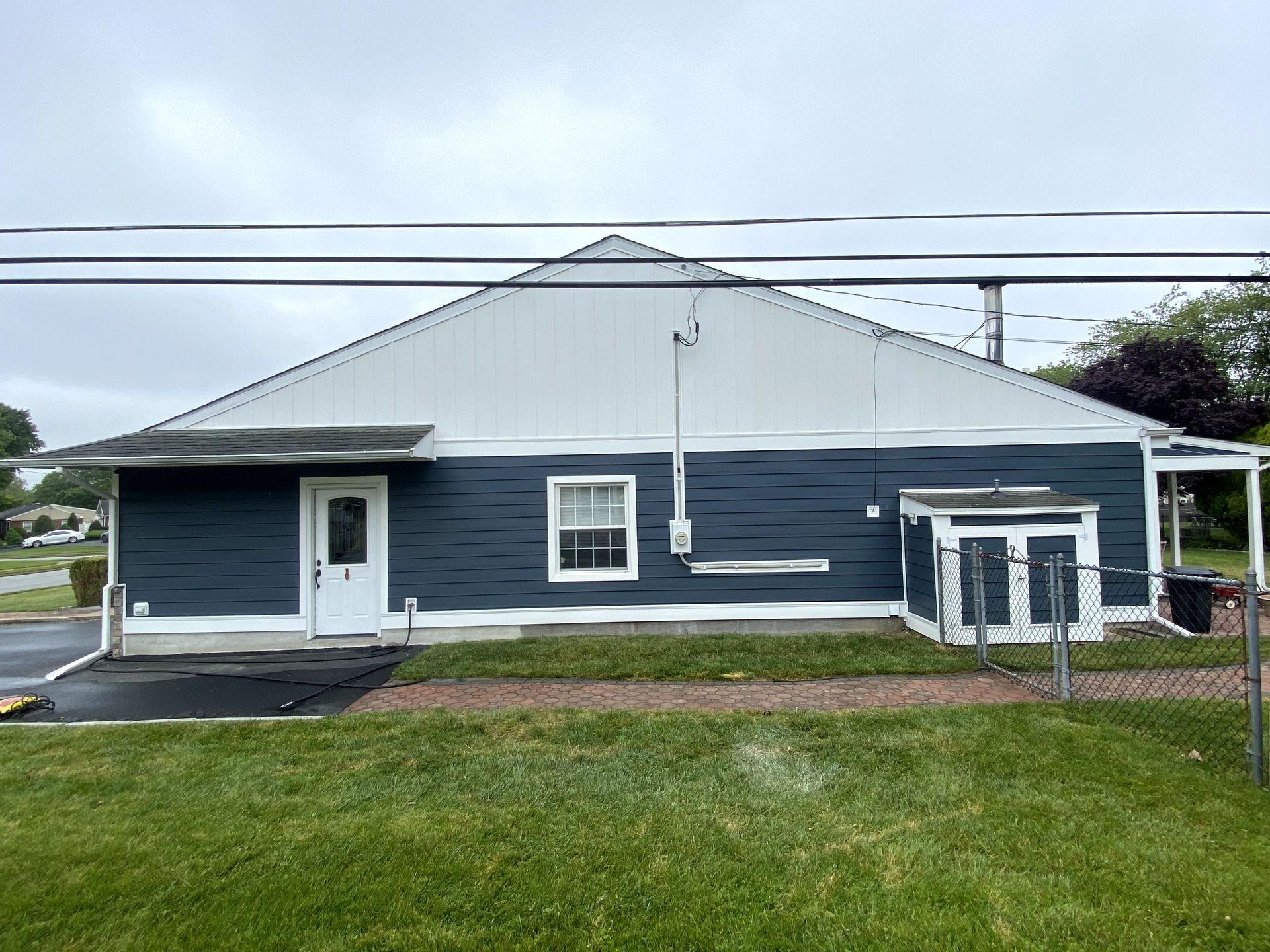 A blue and white house with a porch and a fence in front of it.