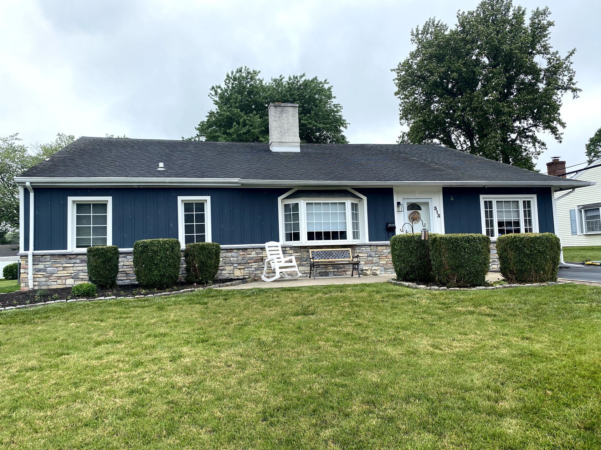 A blue house with a black roof is sitting on top of a lush green lawn.