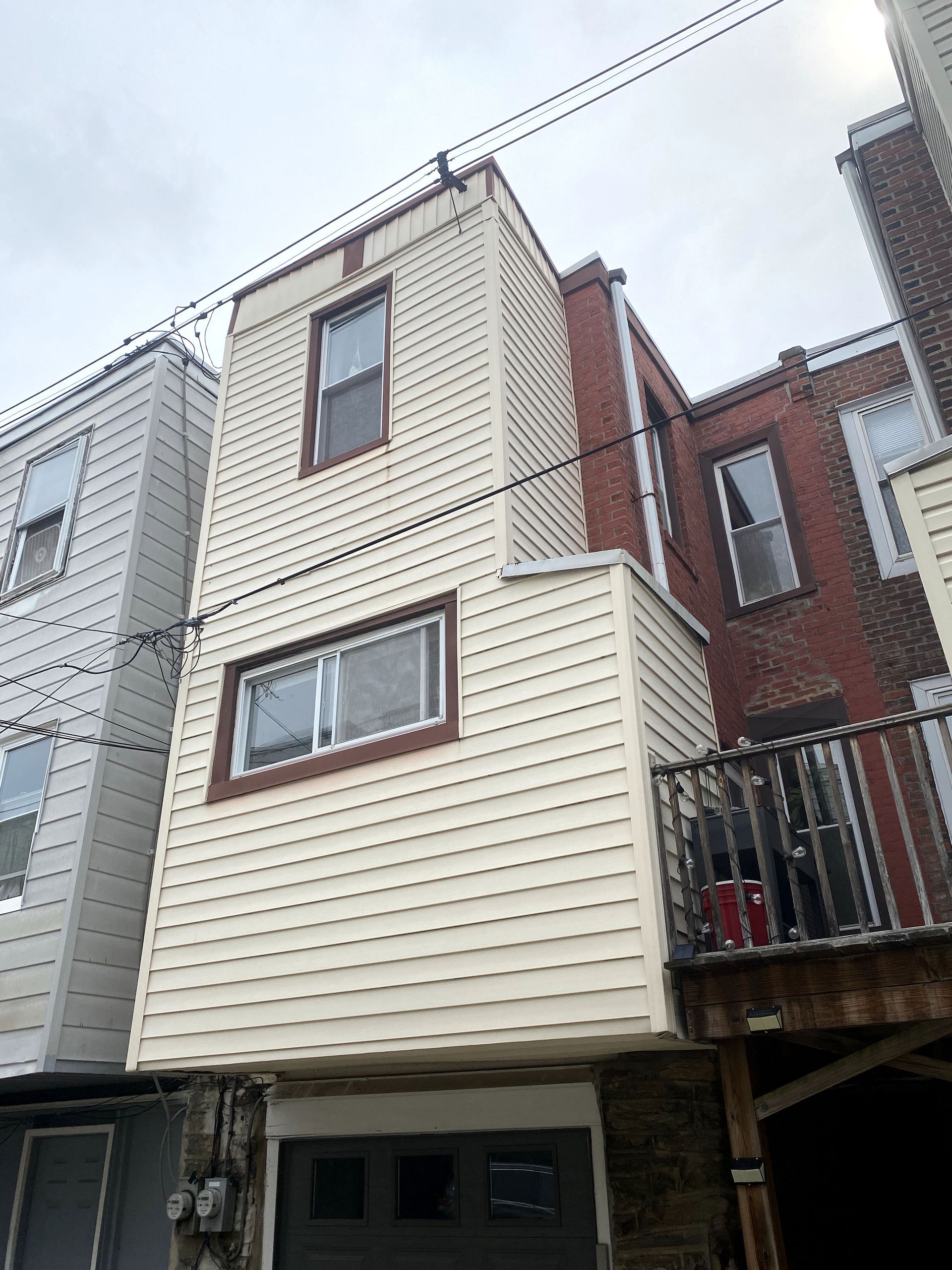 A white house with a balcony is sitting next to a brick building.