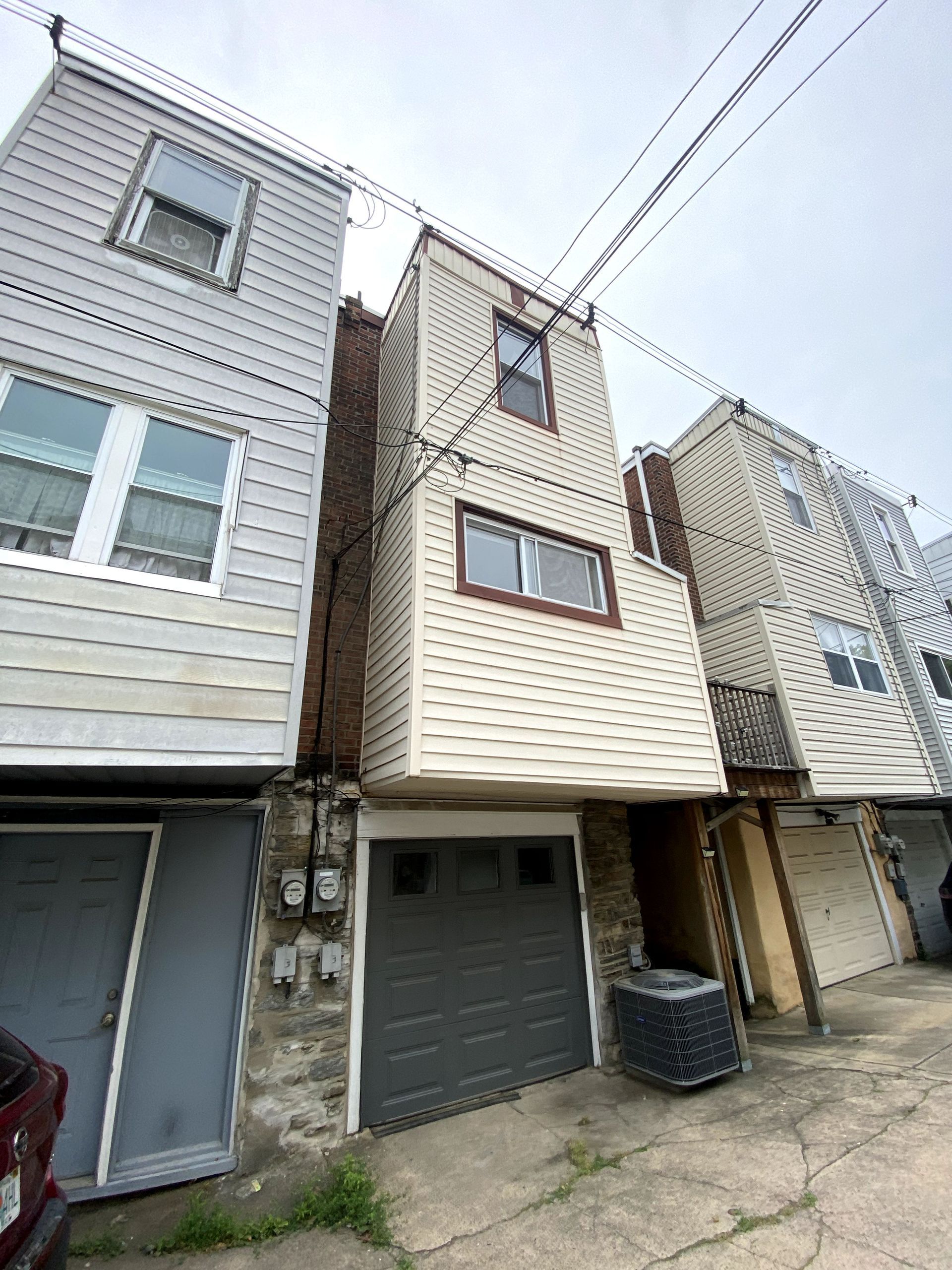 A row of houses with a garage and a car parked in front of them.