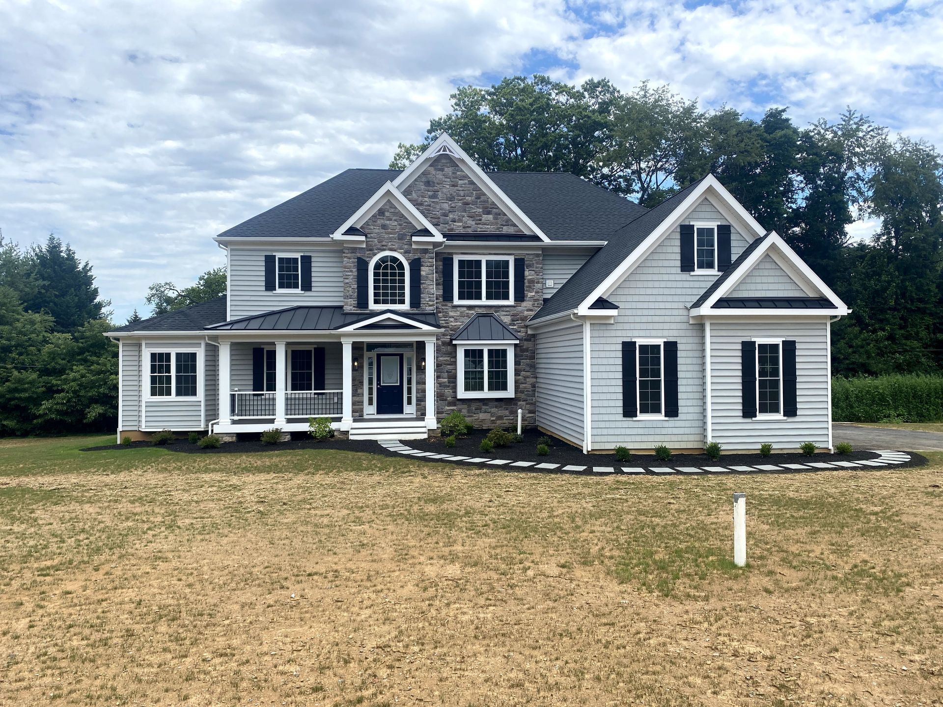 A large white house with a black roof is sitting in the middle of a field.