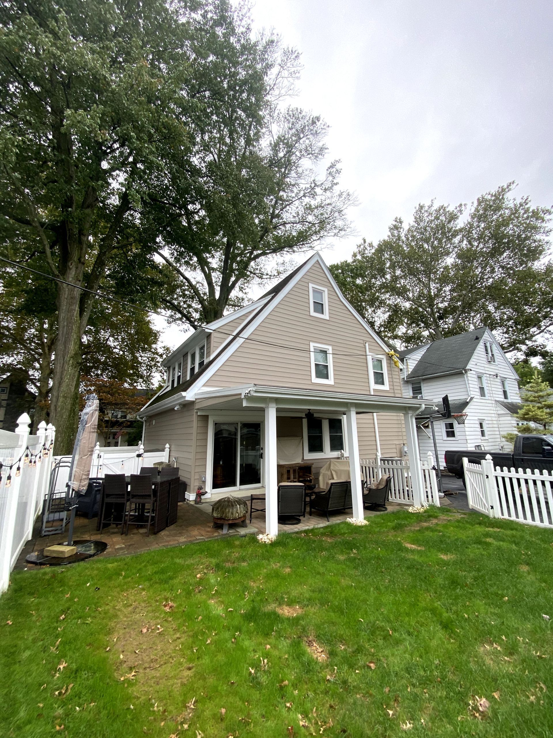 The backyard of a house with a covered porch and a white picket fence.