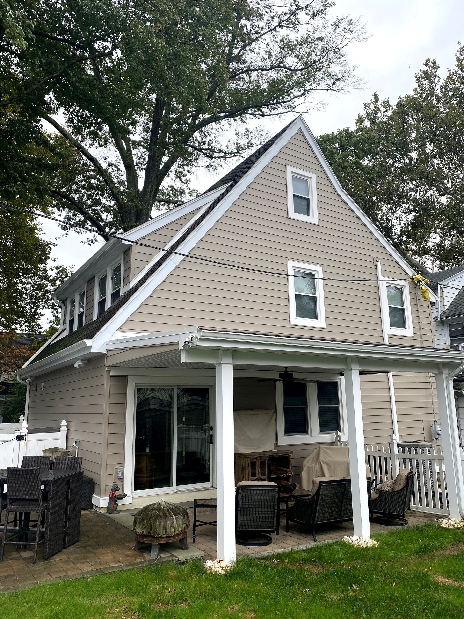 The back of a house with a porch and a tree in the background.