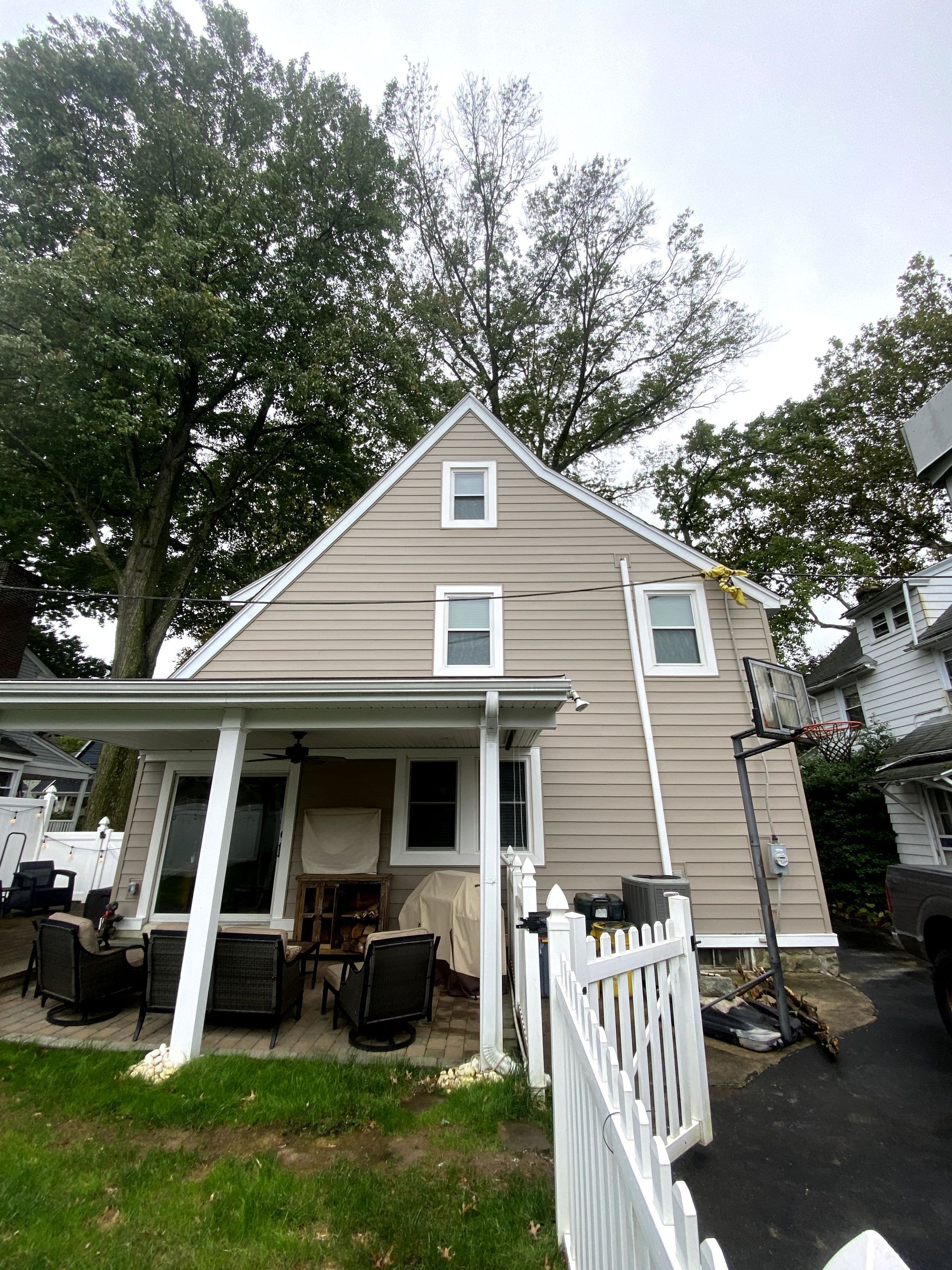 The back of a house with a porch and a white fence.