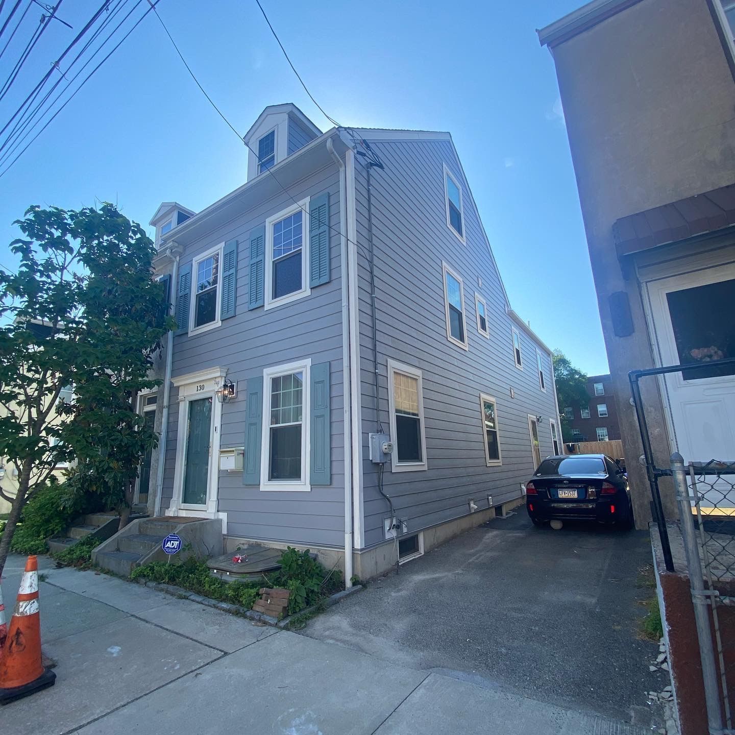 A gray house with a car parked in front of it