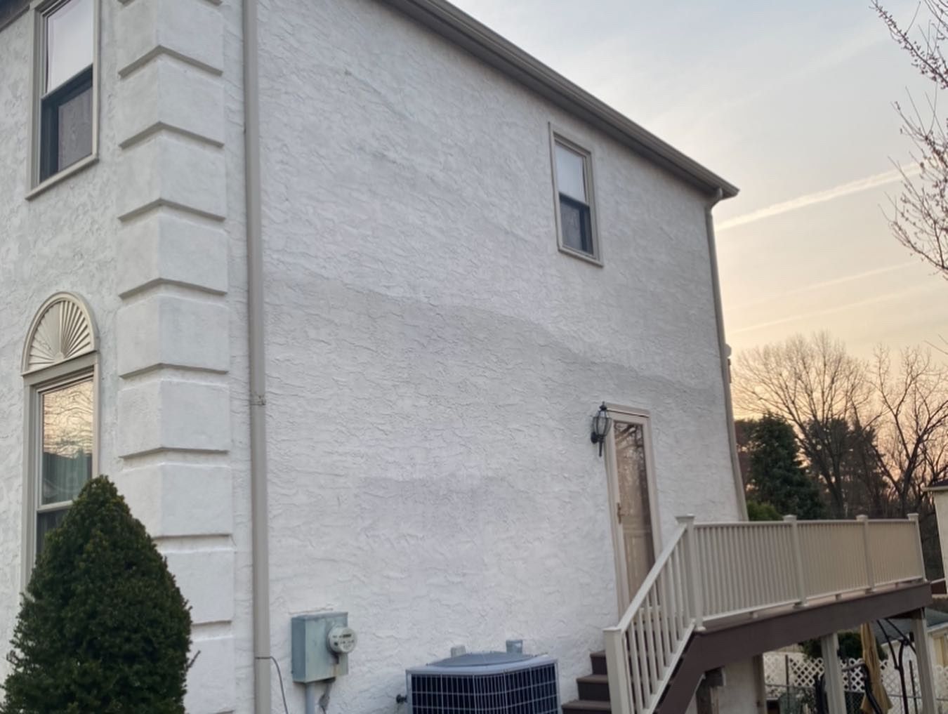 A white house with stairs leading up to the second floor