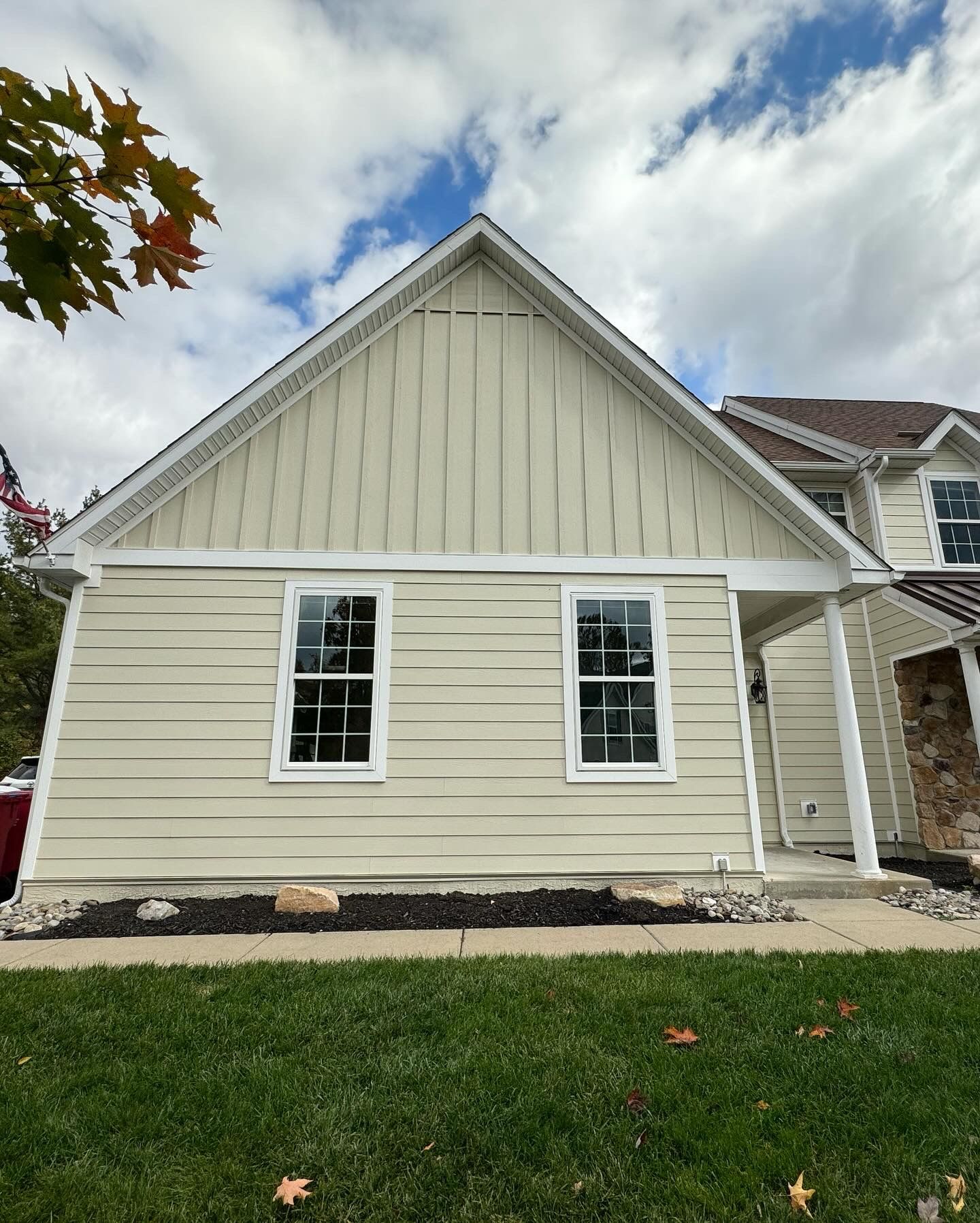 A white house with a roof and a lot of windows is sitting on top of a lush green lawn.