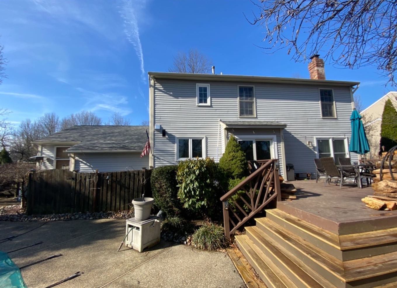 The back of a house with a wooden deck and stairs leading to it.
